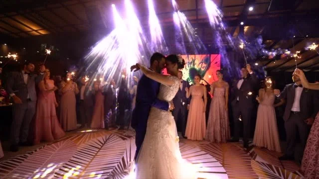 Bride and groom having their first dance with guests surrounding them holding sparklers.