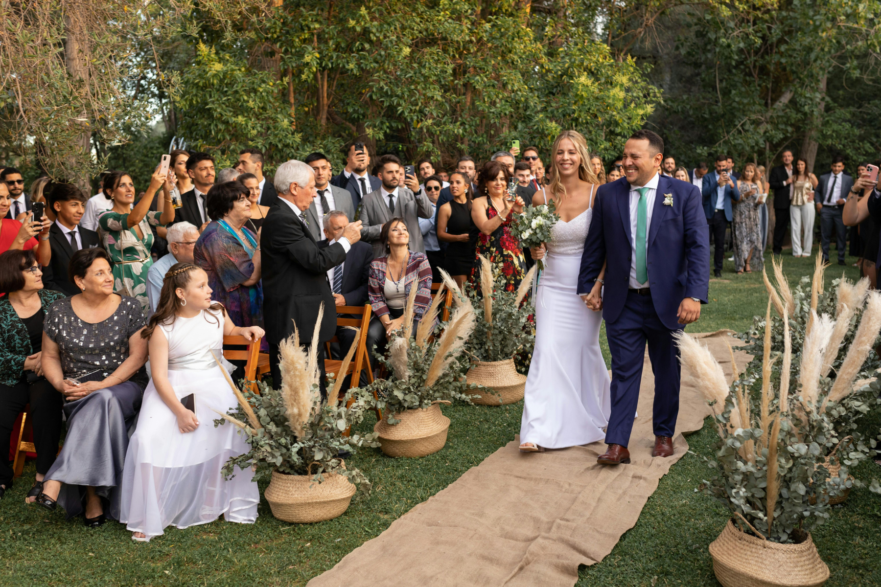 Bride and groom walking down the aisle as all their guests watch.