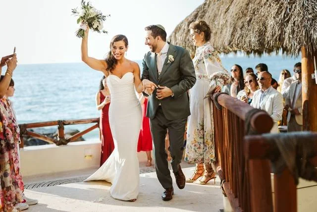 Happy bride raising her bouquet and groom looking at her lovingly
