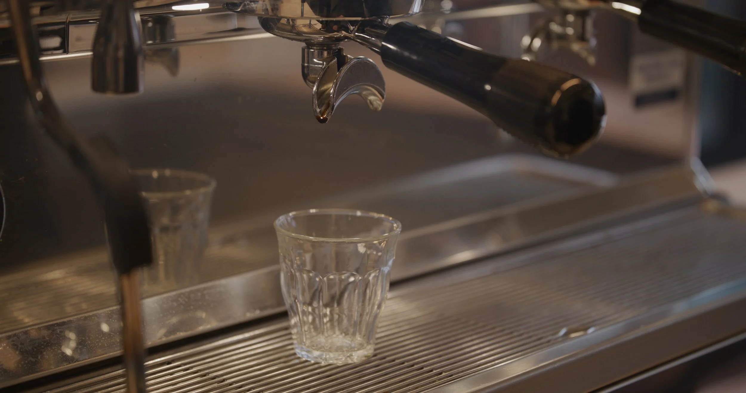 Close-up of an espresso machine dispensing coffee into a glass cup.