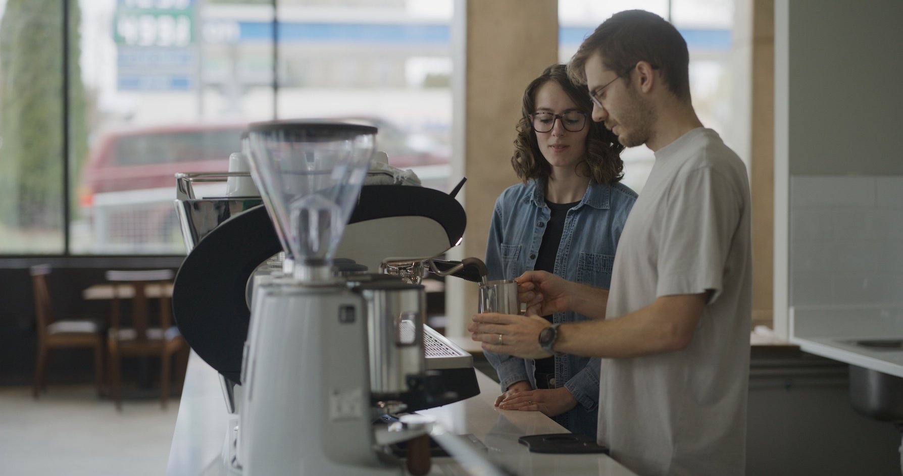 One barista training a new hire through Lighthouse's recovery program on how to pull a great shot of coffee.