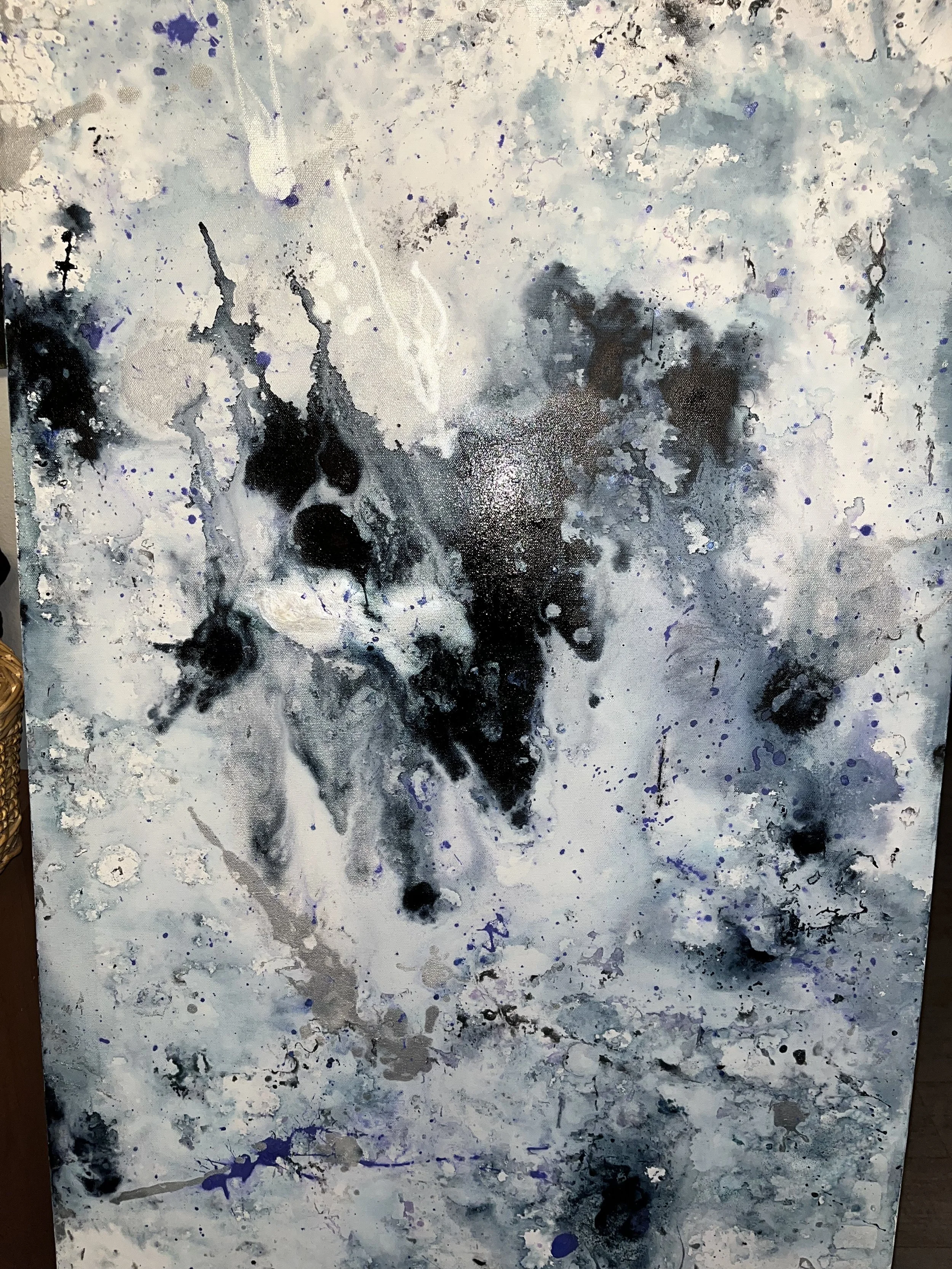 Abstract painting with black, blue, gray, and white splatters and drips.