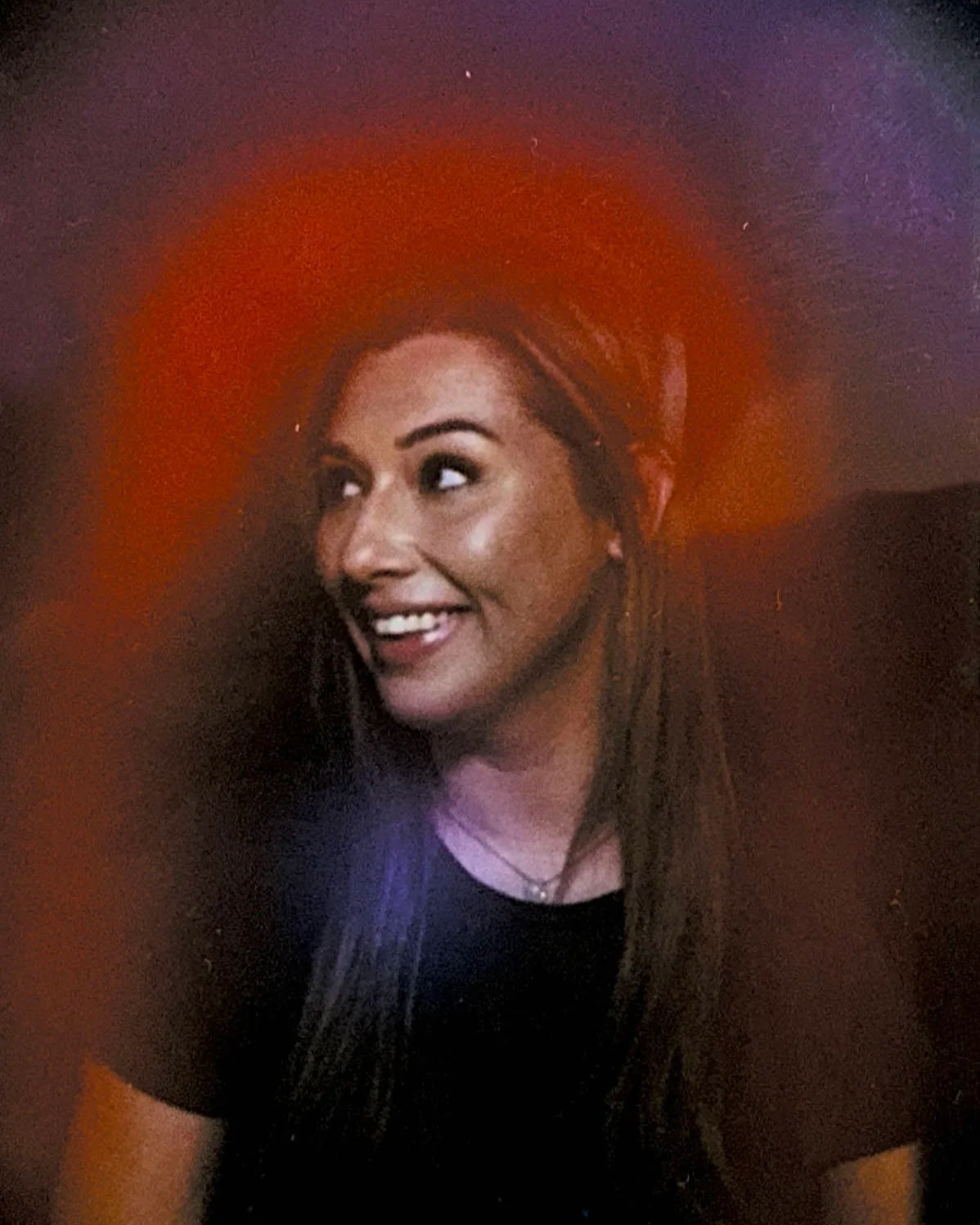 Julia Stewart, astrologer and founder of Stardust Astro Events, smiling within a vibrant red and orange aura reading photo.