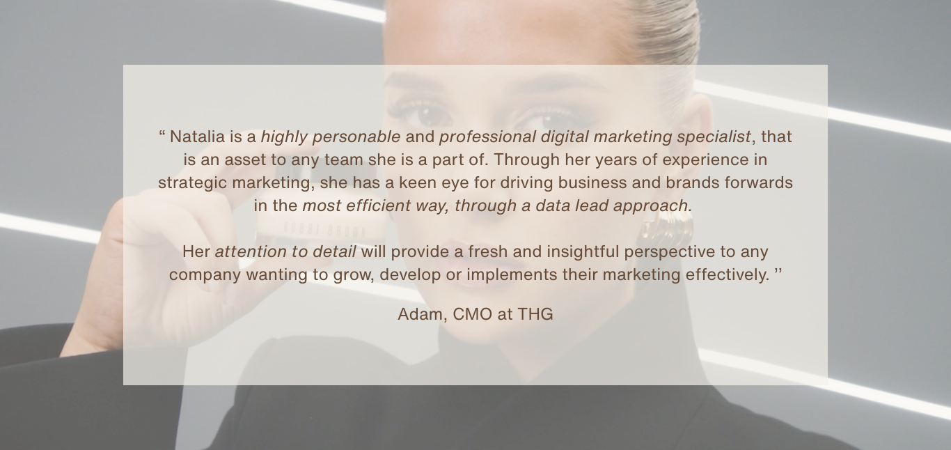 A woman with blonde hair lit by overhead lights in a modern office, holding a business card close to her face.