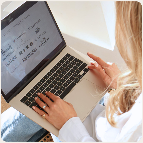 A woman with blonde hair typing on a silver laptop with black keyboard, viewing a document on the screen.