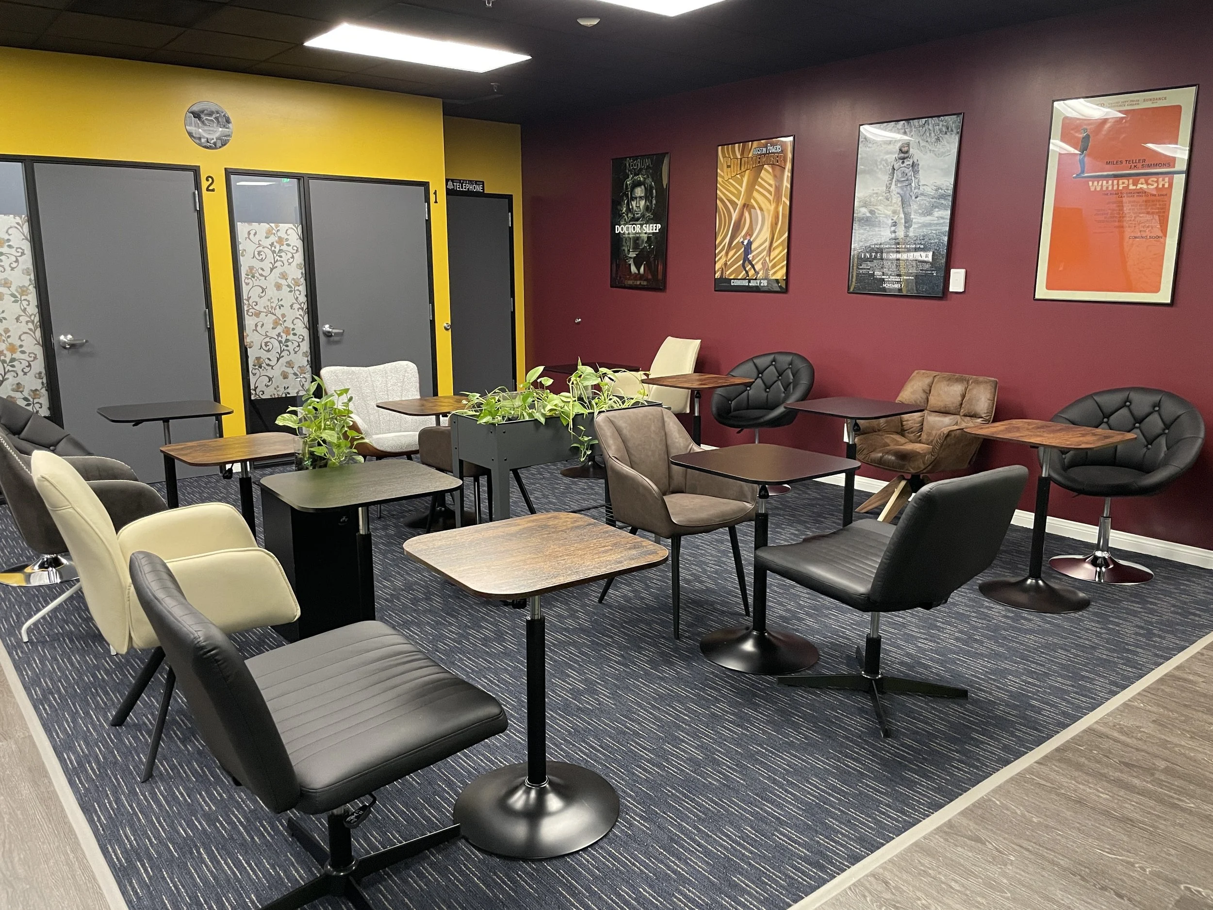 An office with three black ergonomic chairs and a desk arranged near a large window with city and mountain views.
