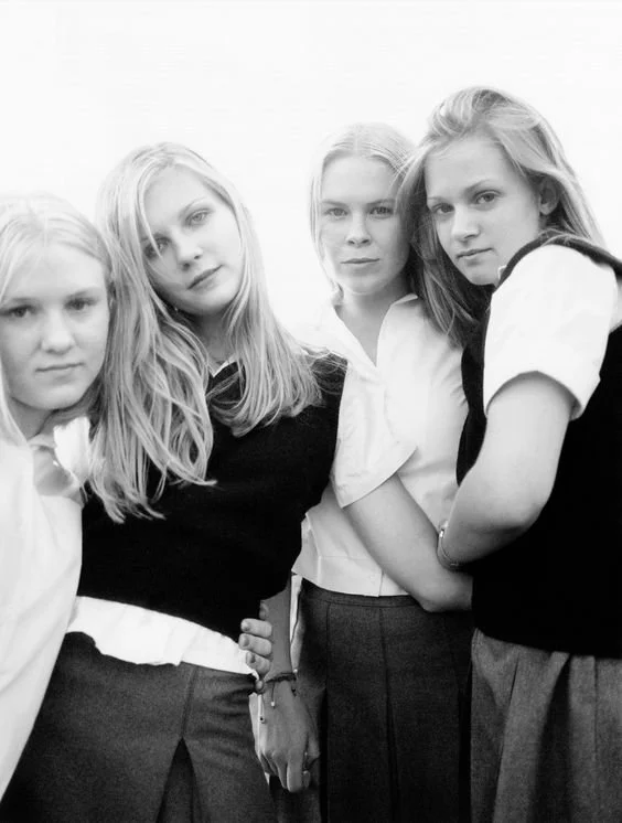 Four teenage girls wearing school uniforms posing together for a photo, black and white image.