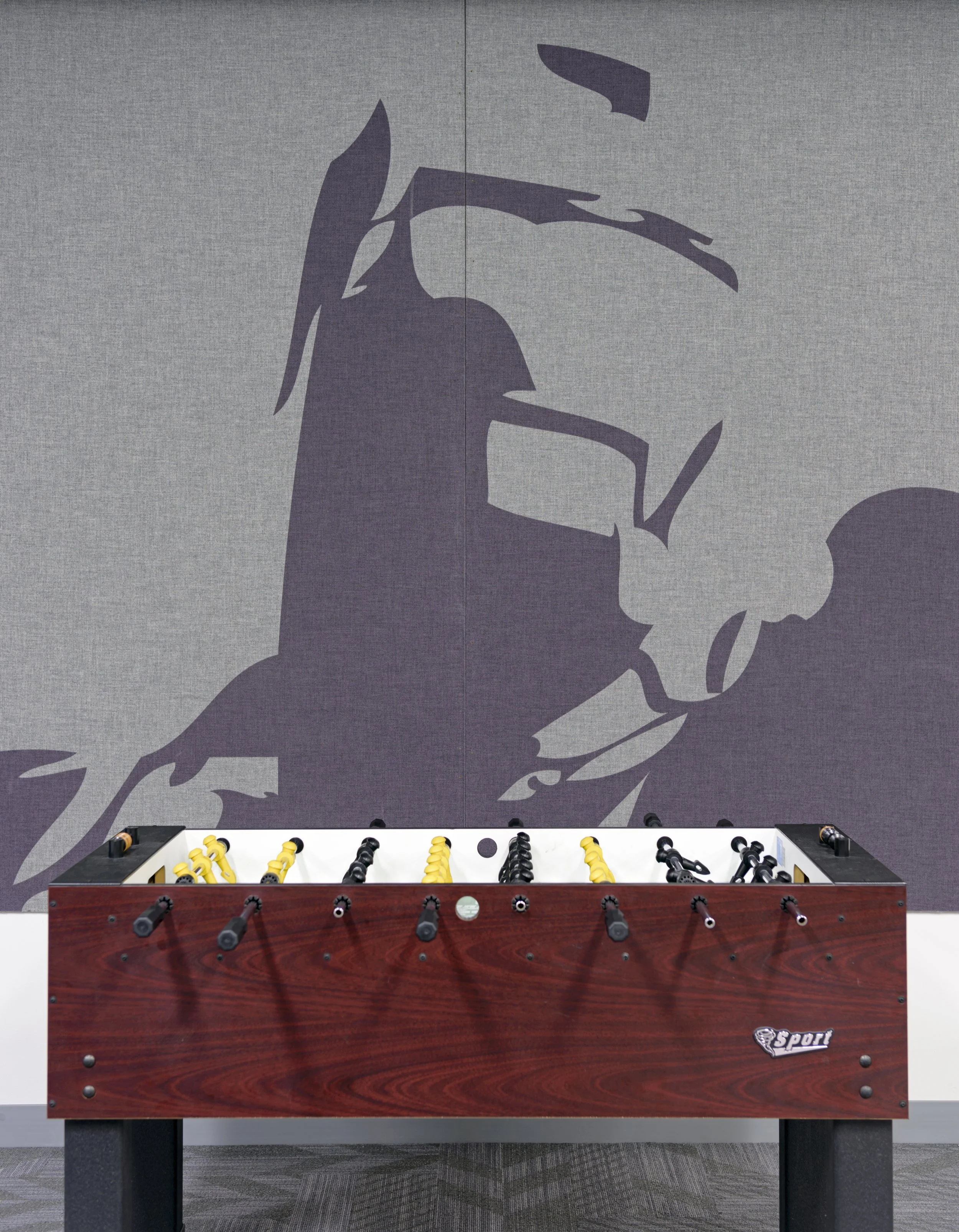 Foosball table in front of a wall with a large abstract mural of a scorpion.