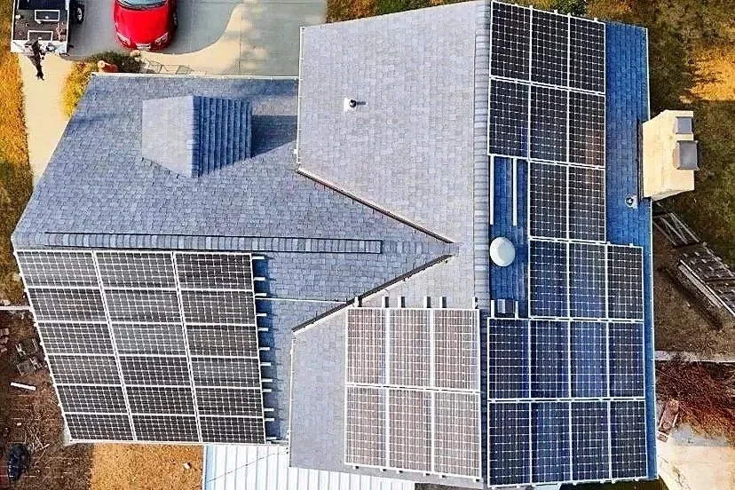 Aerial view of a house with multiple solar panels installed on the roof.