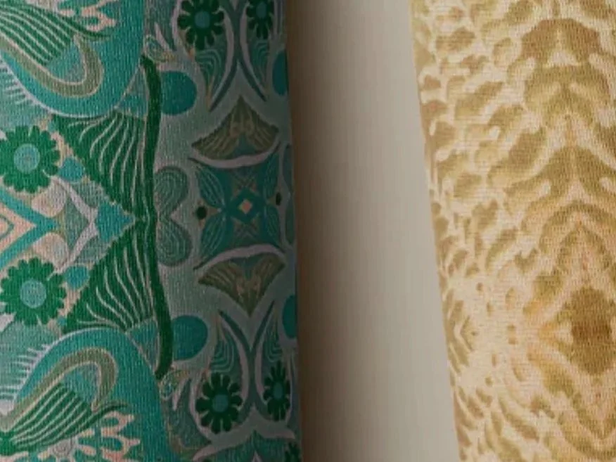 Close-up of fabric patterns, one with green and teal floral design, another with yellow and beige textured pattern.