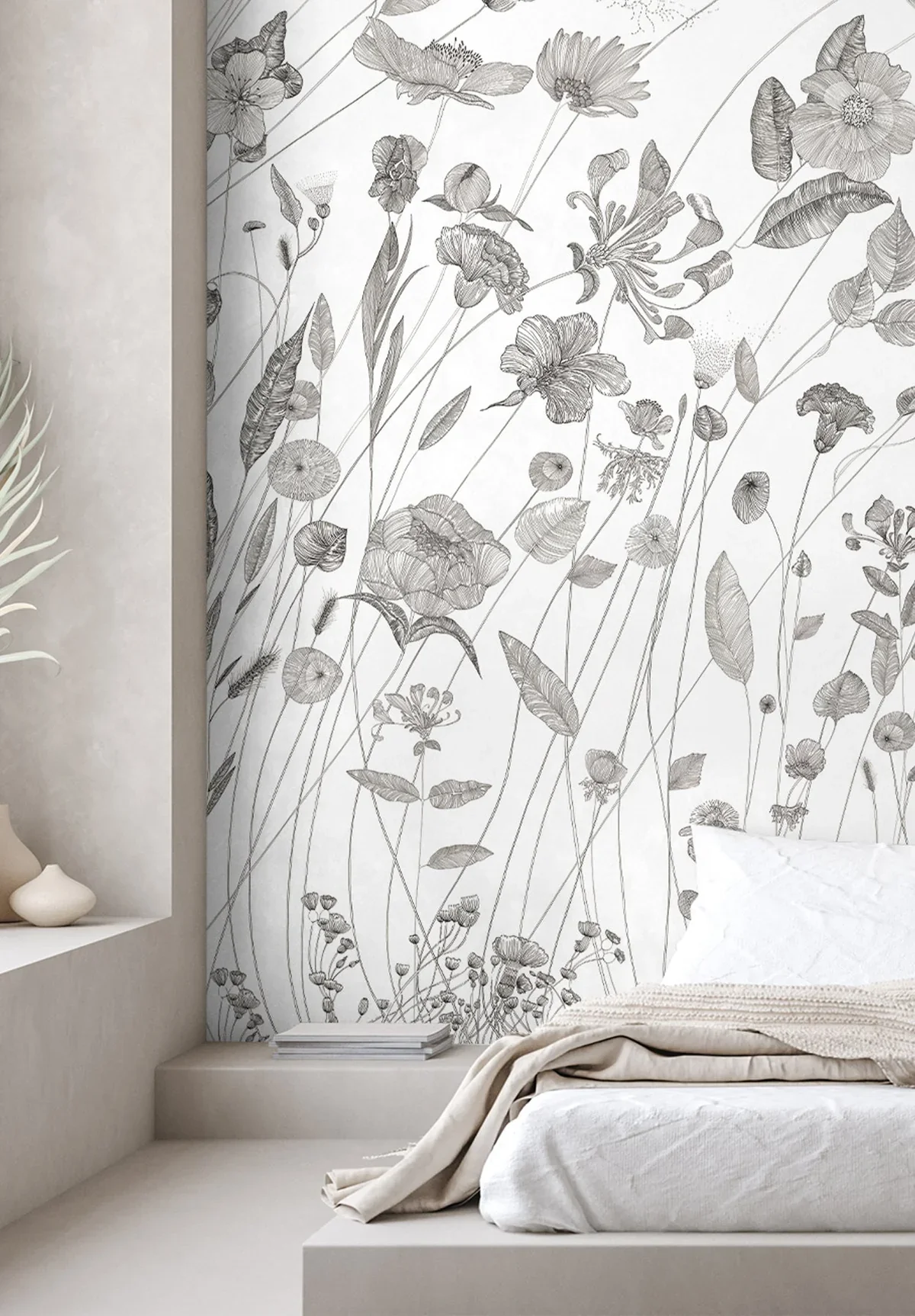 Close-up of a bedroom with a white bed, beige blanket, and white pillow, against a wall with black and white floral and botanical patterned wallpaper.