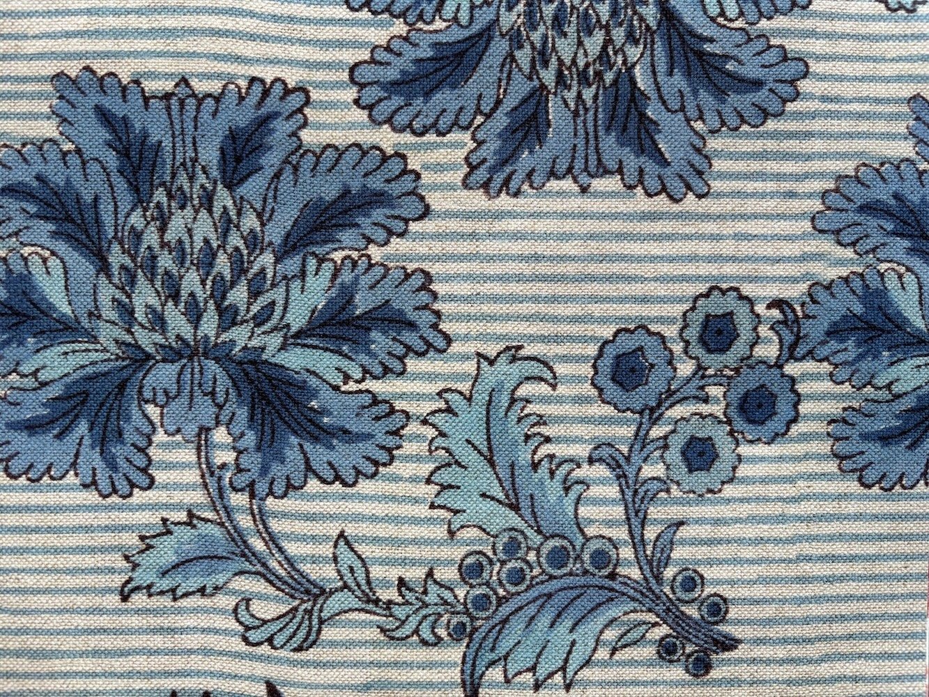 Close-up of a fabric with a blue floral pattern on a background of fine horizontal stripes.