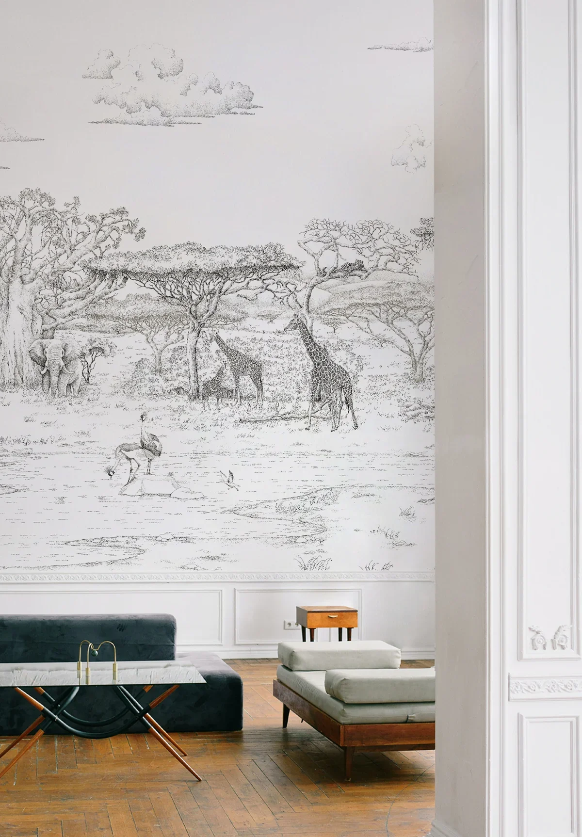 A wall mural depicting a safari scene with trees, giraffes, and elephants in black and white.