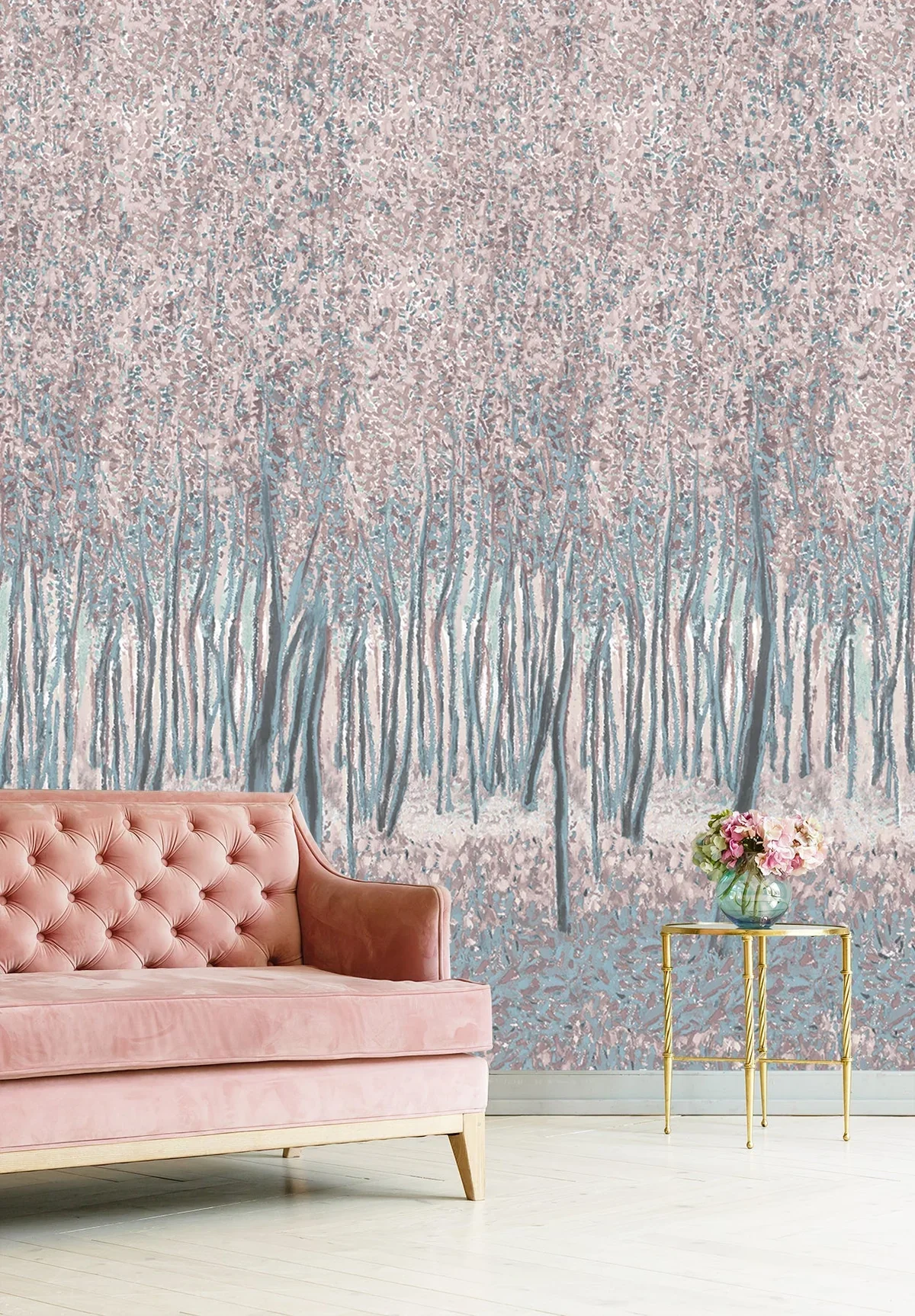 A pink velvet tufted sofa, a gold side table with a glass vase of pink flowers, and a large wall mural of a pastel-colored forest scene with trees and blossoms.