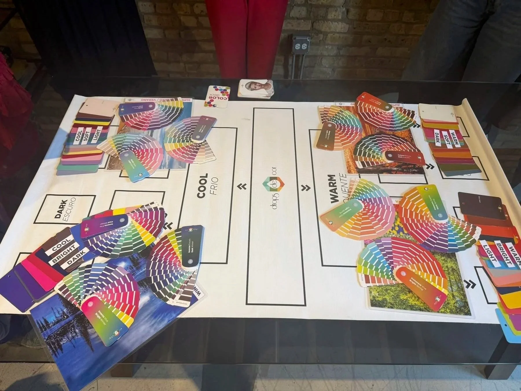A color sorting game on a table with a chart of color categories and piles of color sample cards divided into sections labeled dark, cool, warm, and bright.