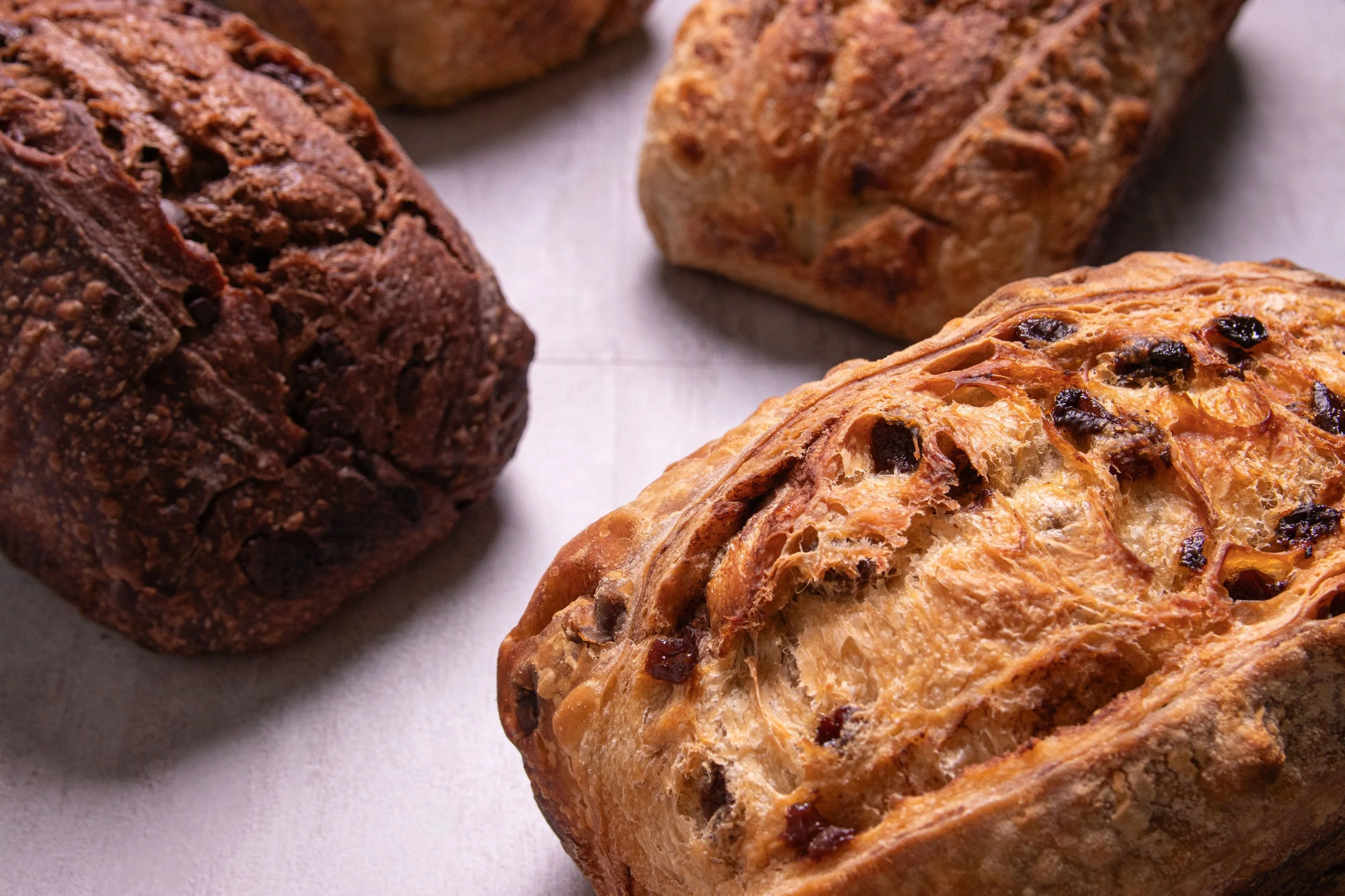 Four loaves of sourdough bread on a white paper surface.