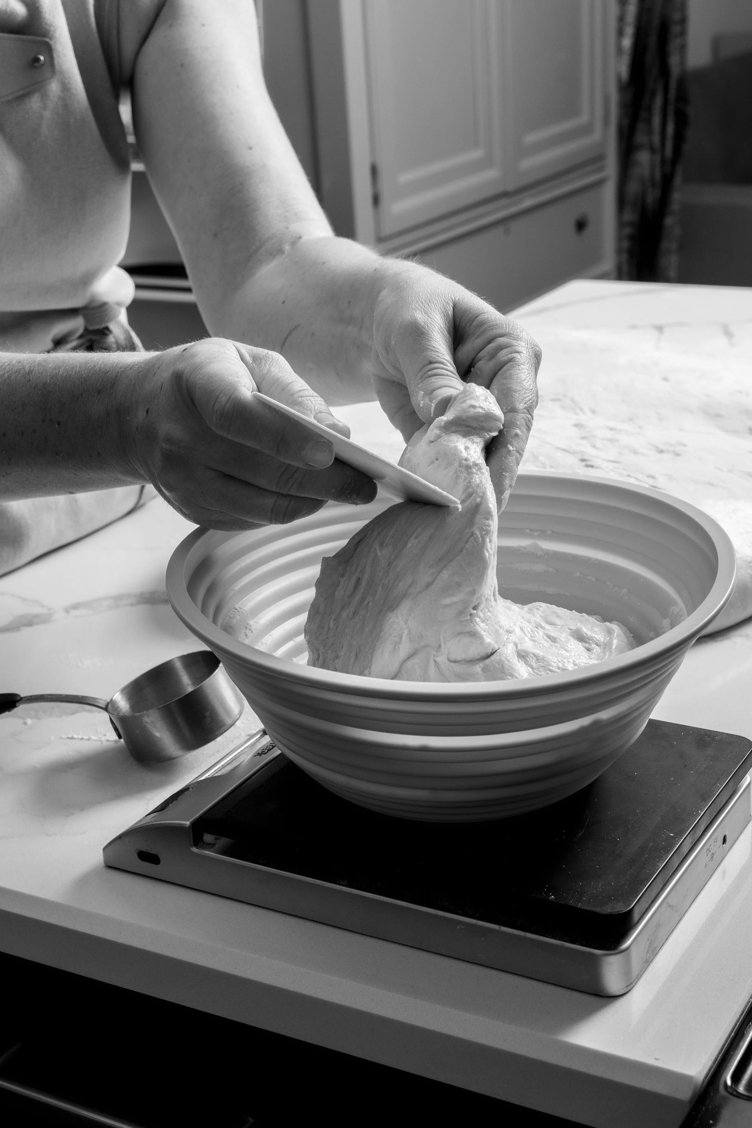 Person kneading dough in a bowl on a kitchen counter.