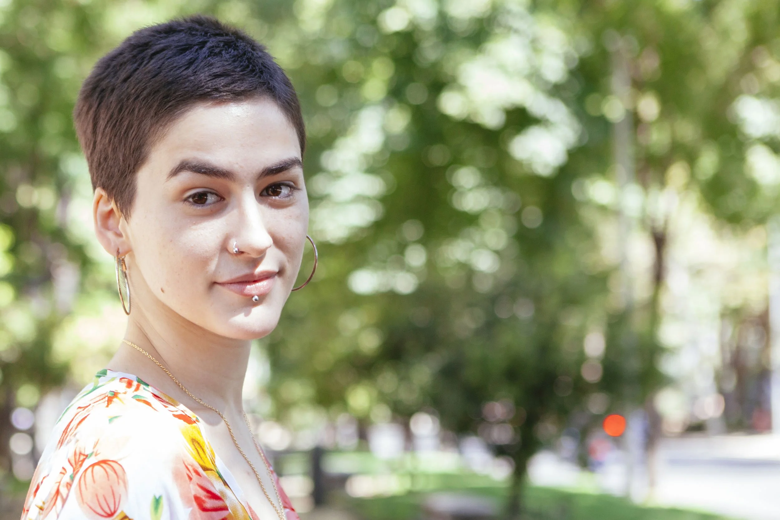 person with short hair smiling out in nature