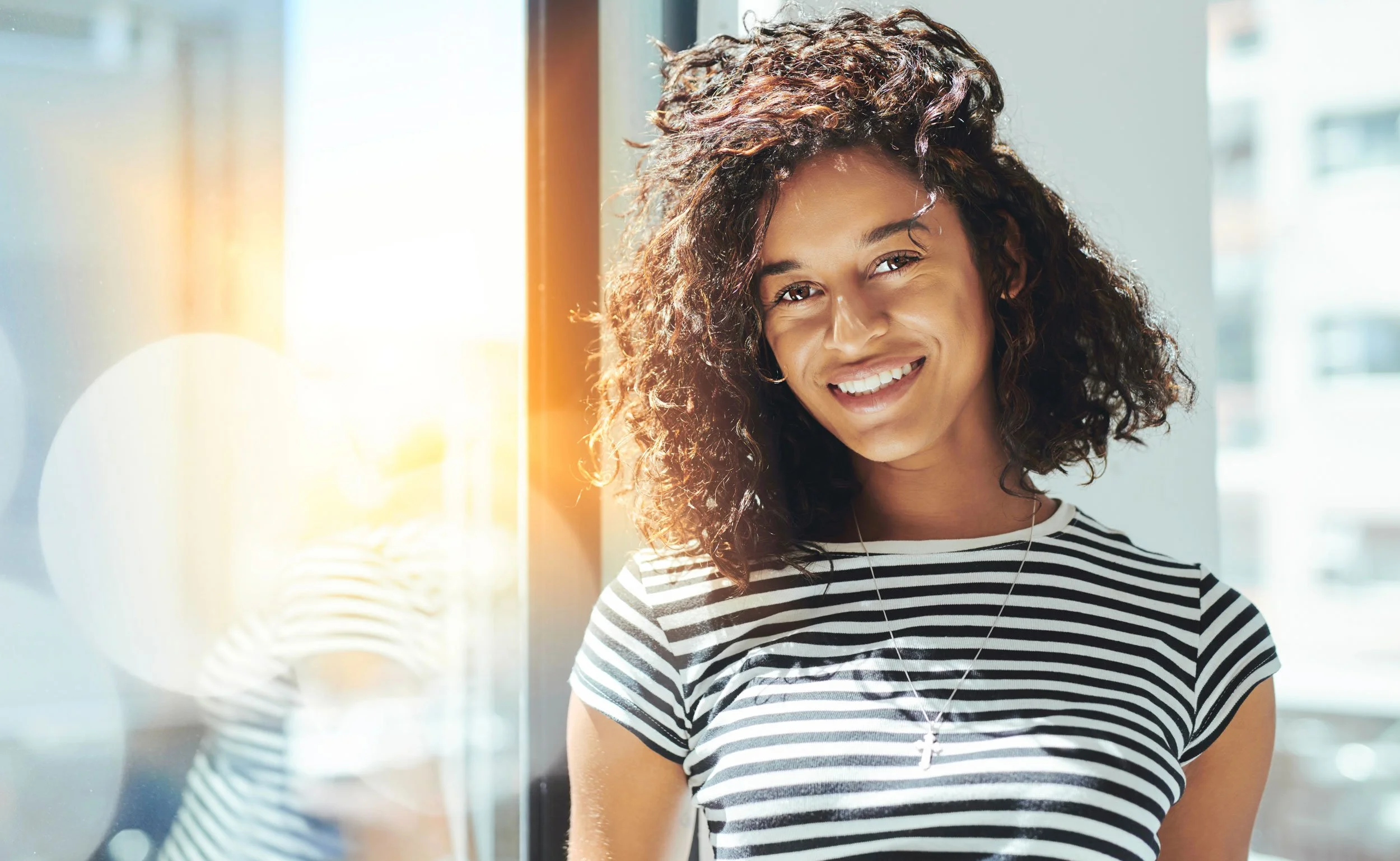 woman with curly hair smiling in the sun