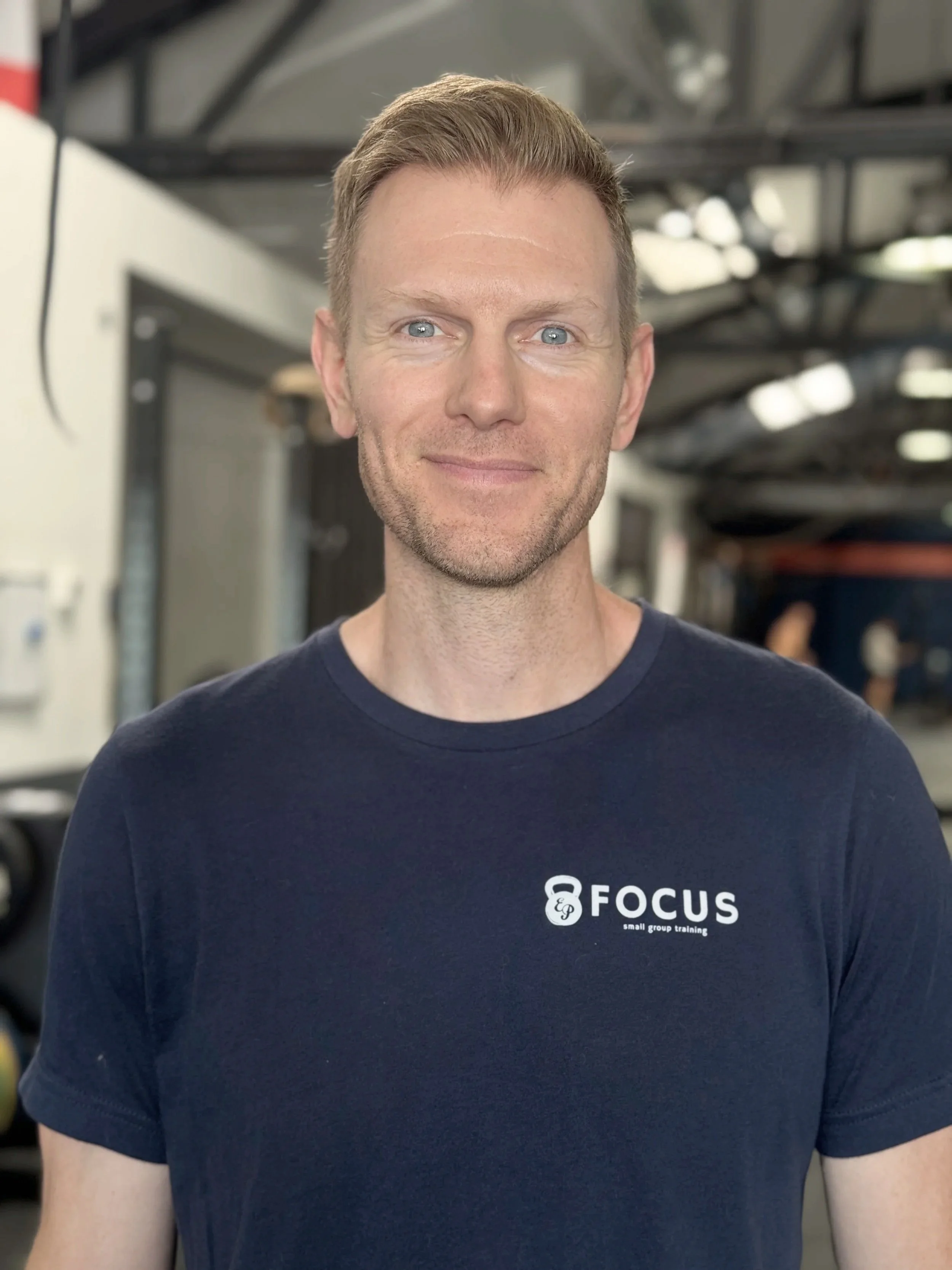 A male coach smiles for a picture