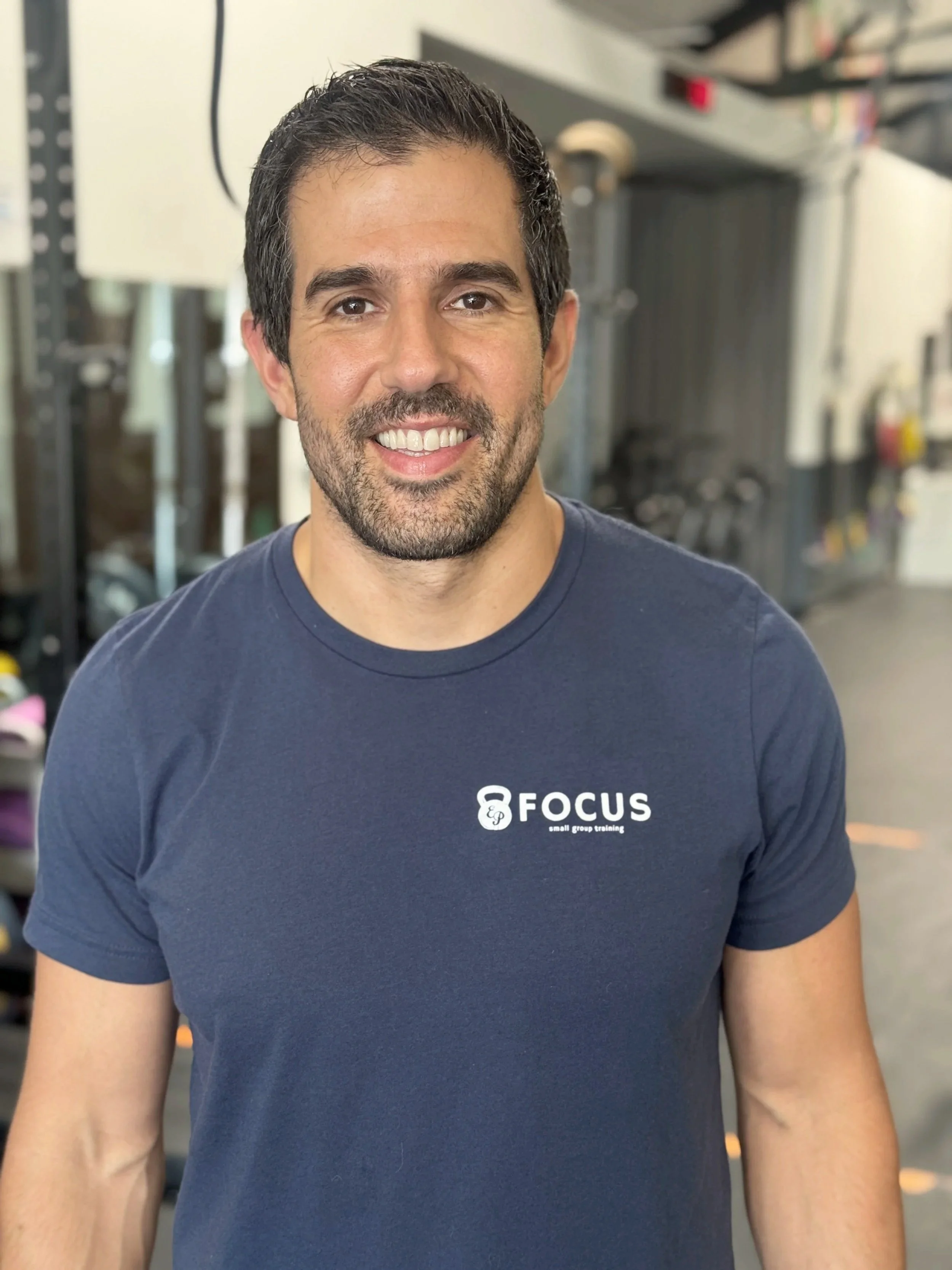 A male coach smiles at the camera for a profile picture