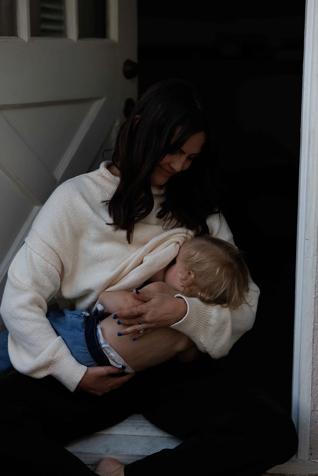 mom breastfeeding child in doorway