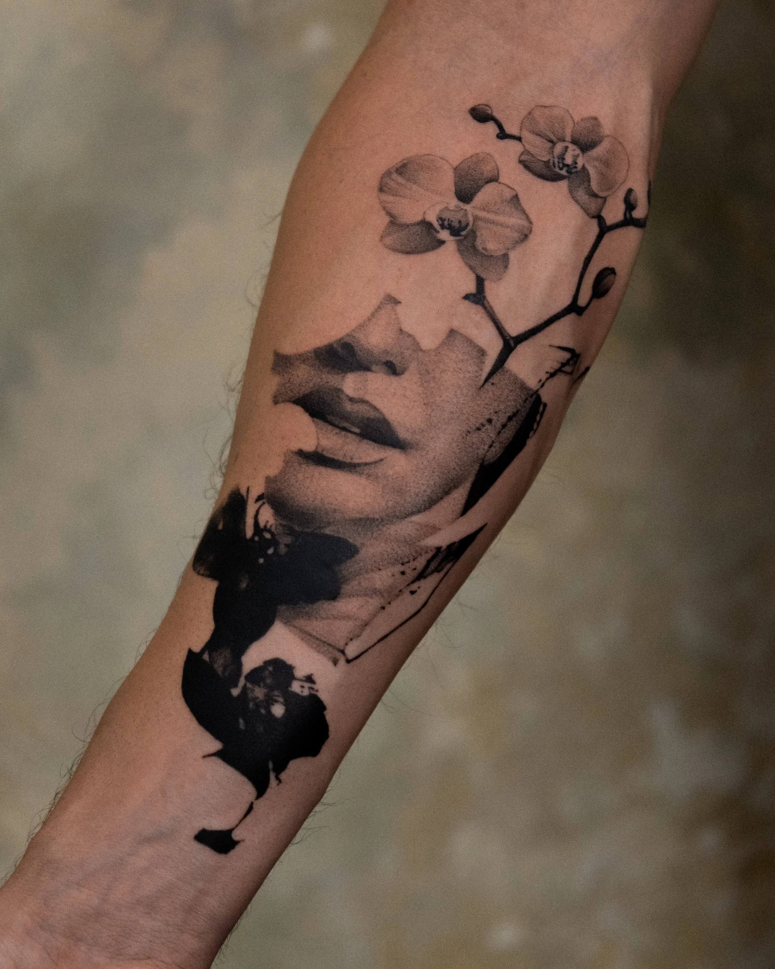 Tattoo of a woman's face with a branch of orchids on her cheek and forehead on an arm.
