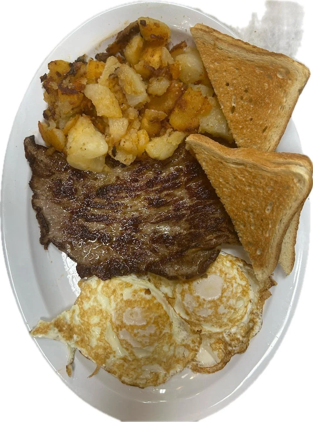 Breakfast plate with fried eggs, grilled steak, home fries, and toasted bread.