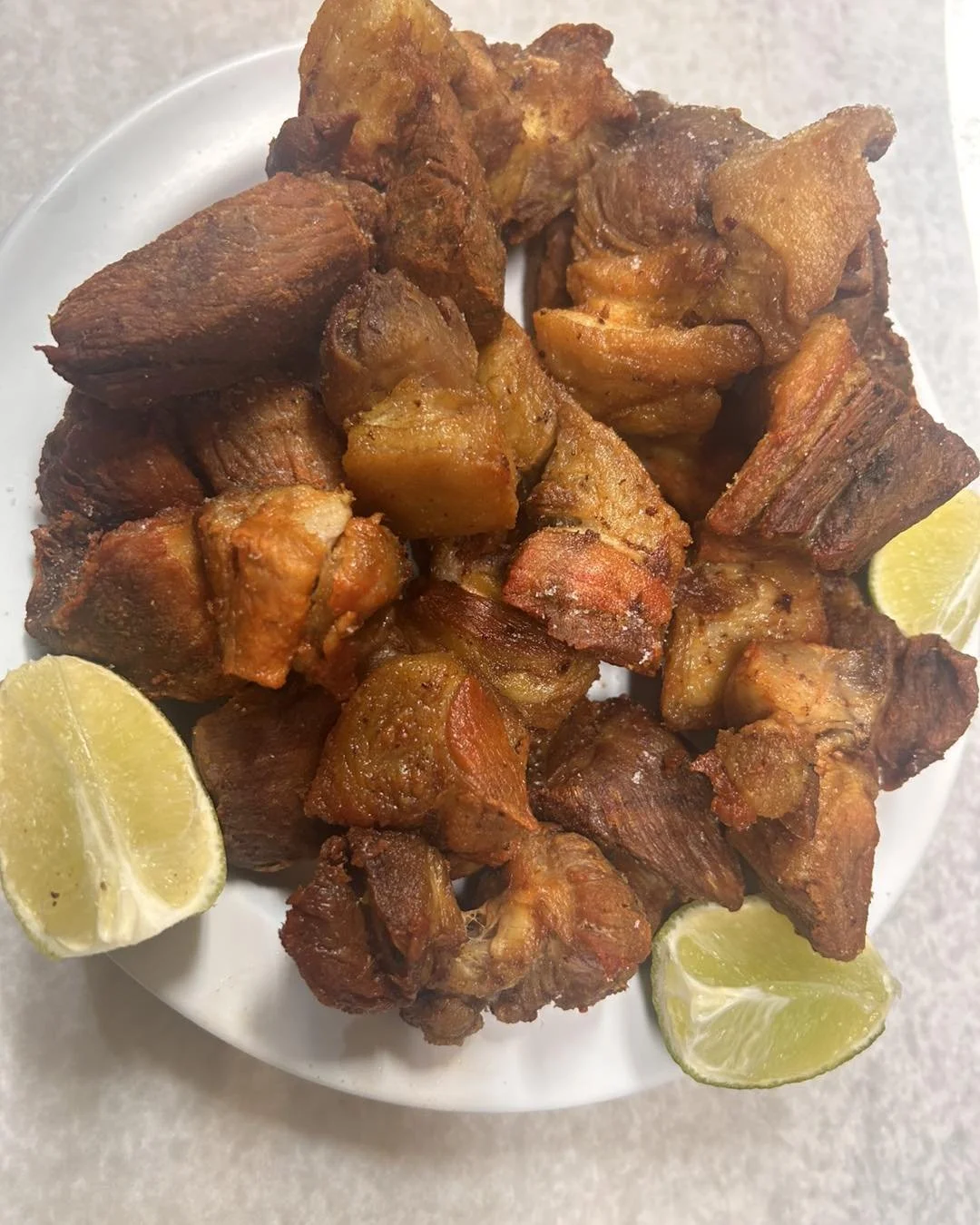 Fried pork, known as chicharrones, with lemon wedges.