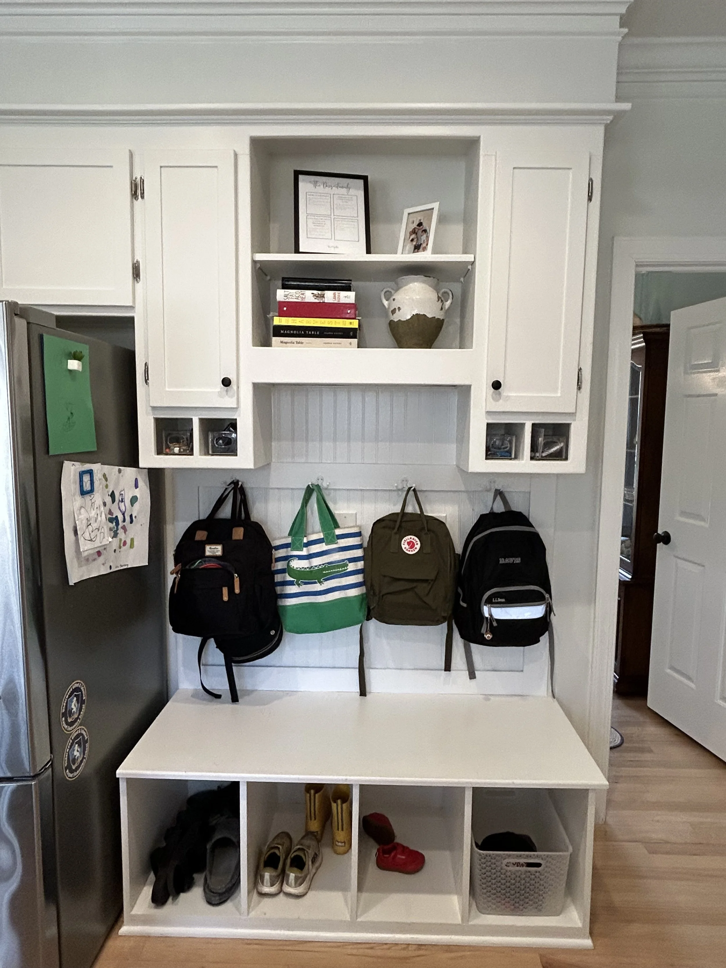 Organized entryway with shelves and hooks holding kids backpacks and shoes