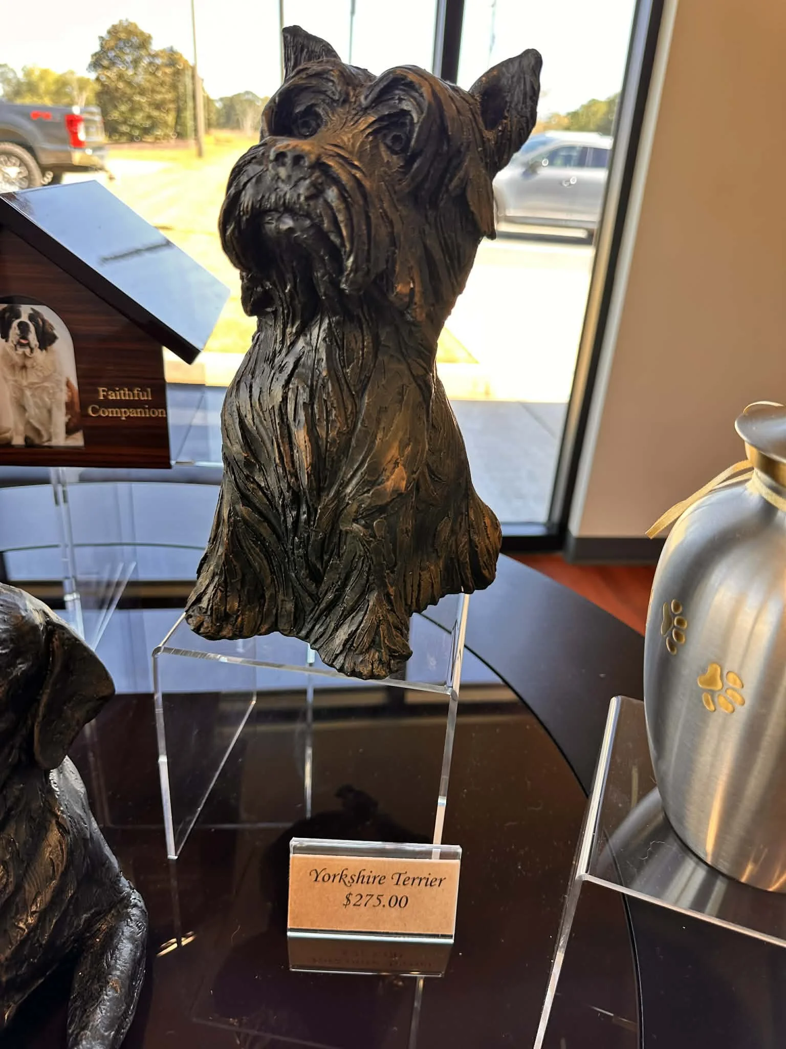 Wooden sculpture of a Yorkshire Terrier dog with a sign reading 'Yorkshire Terrier $275.00' displayed nearby.