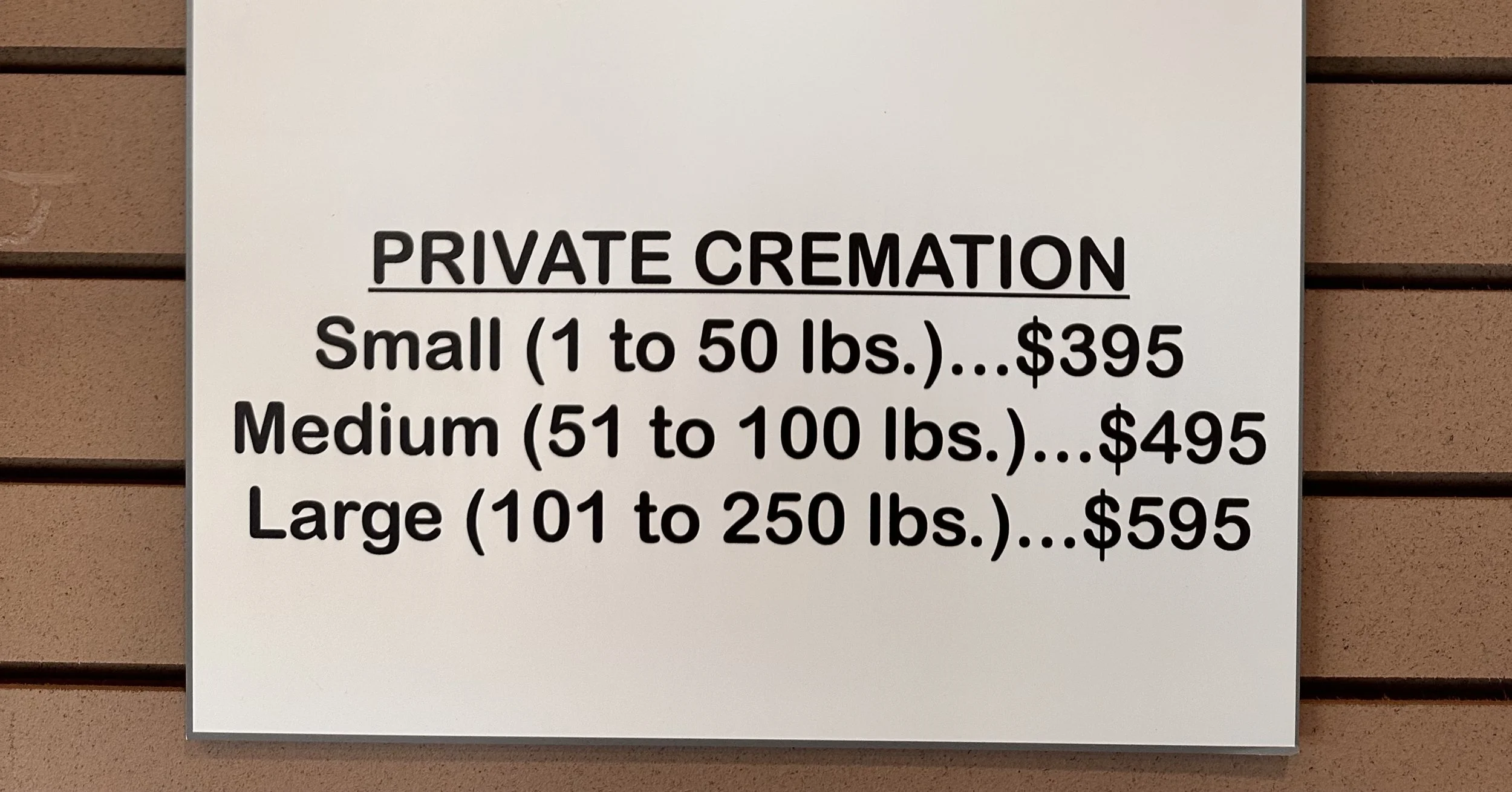 Sign displaying pricing for private cremation services with small, medium, and large options based on weight, priced at $395, $495, and $595 respectively.