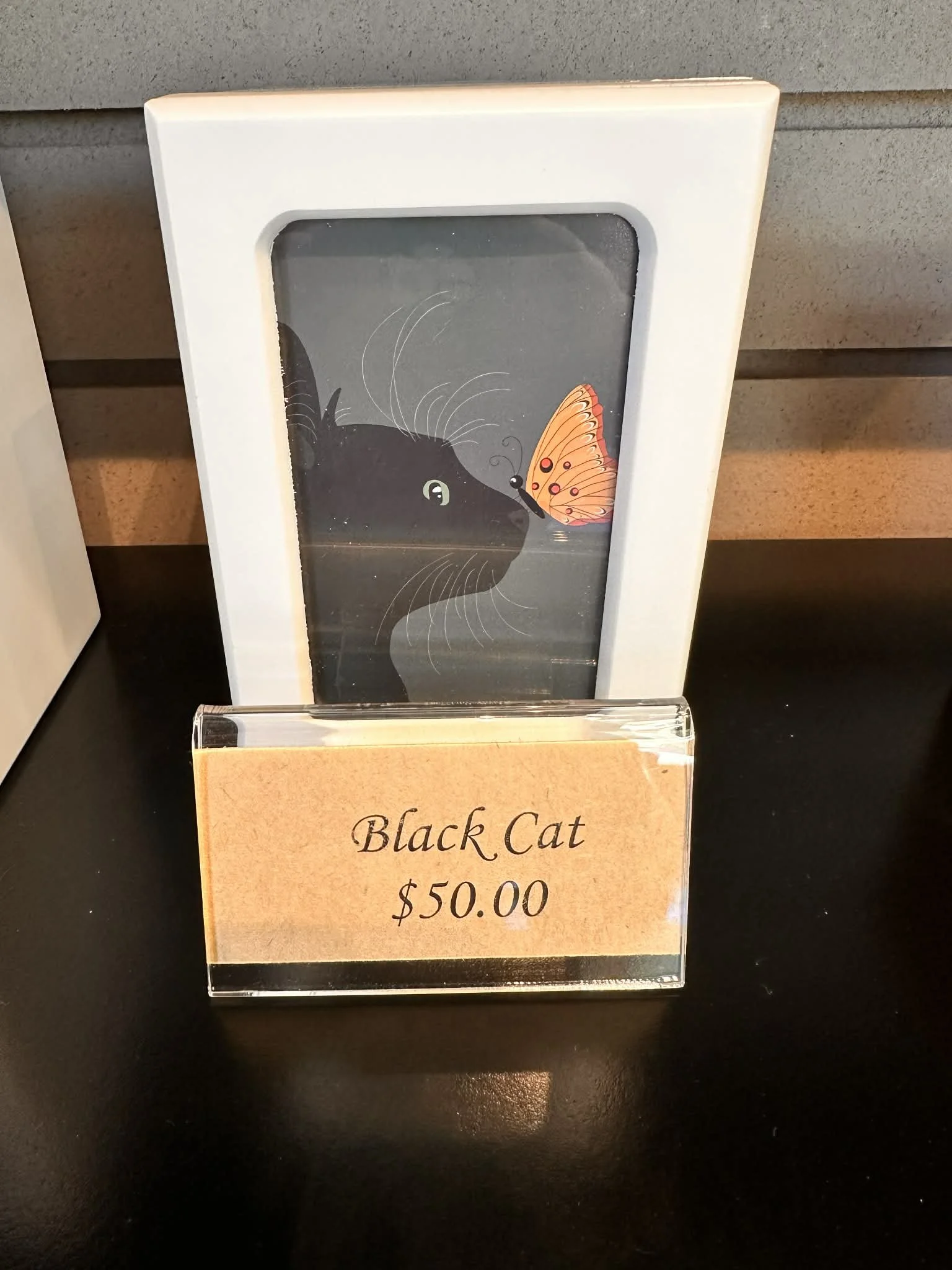 A sign for a Black Cat artwork priced at $50.00, with a depiction of a black cat and a butterfly.