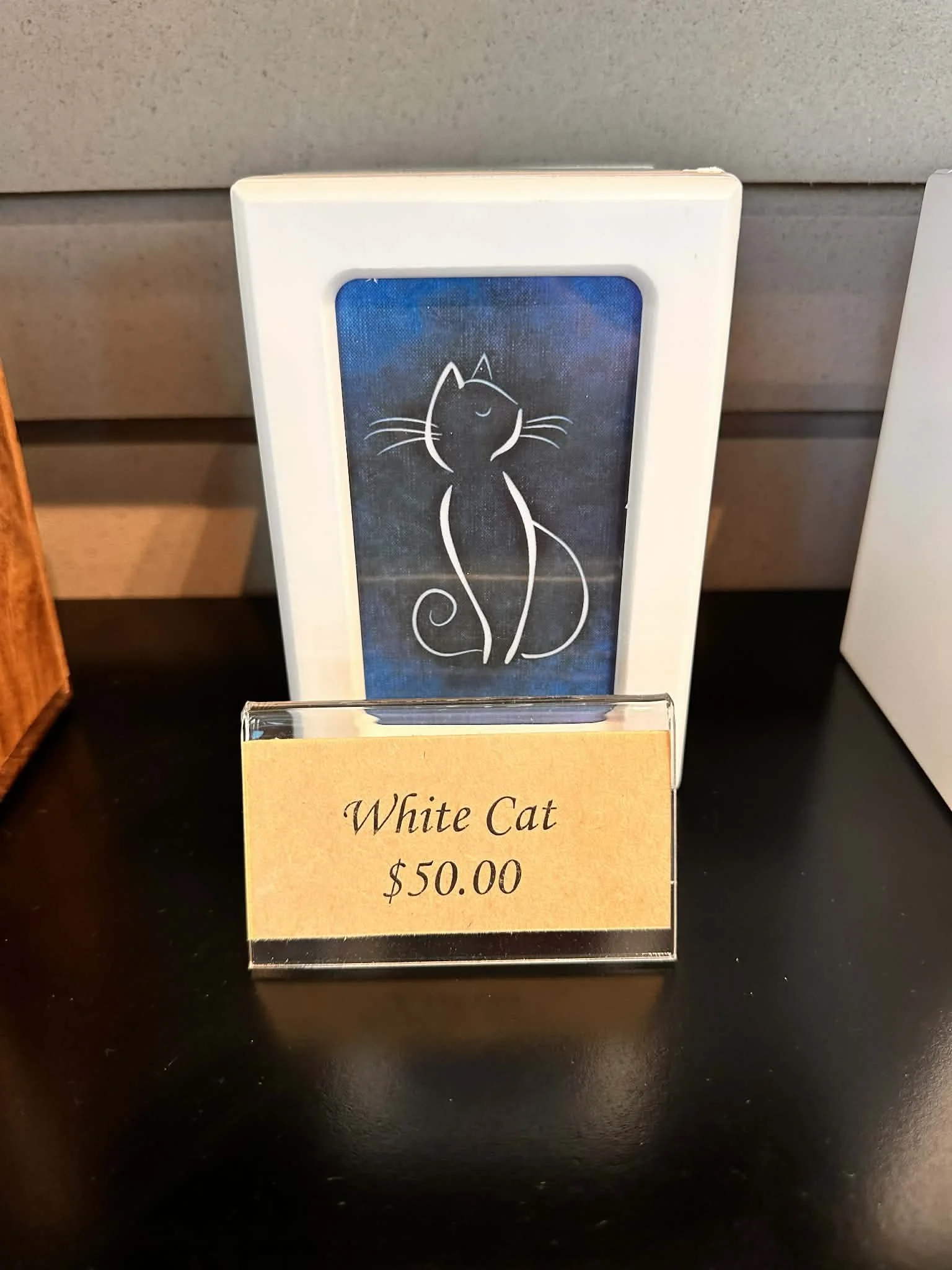 Sign with a drawing of a white cat and the words 'White Cat $50.00'.
