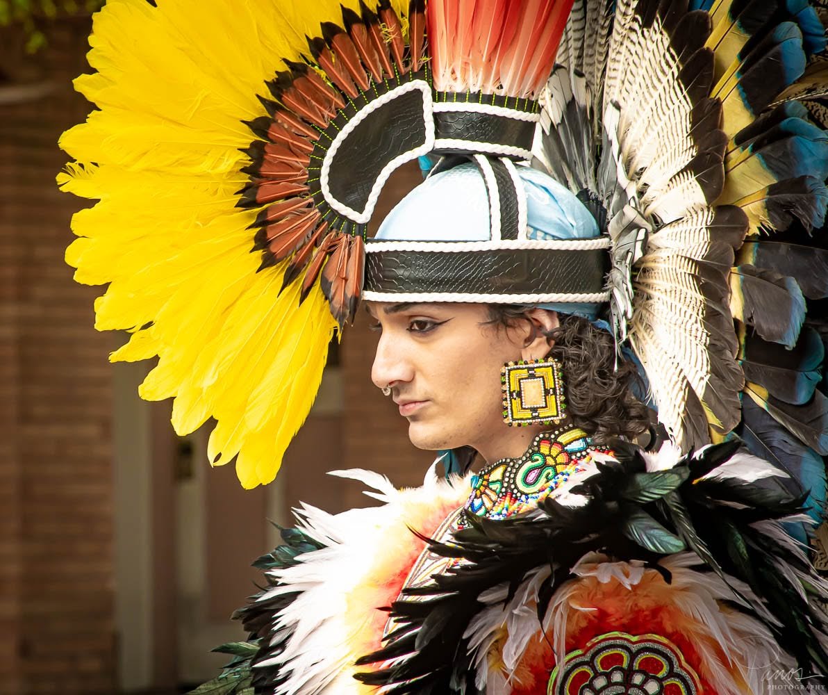 Aztec dancer in traditional ceremonial regalia and feathered headdress.