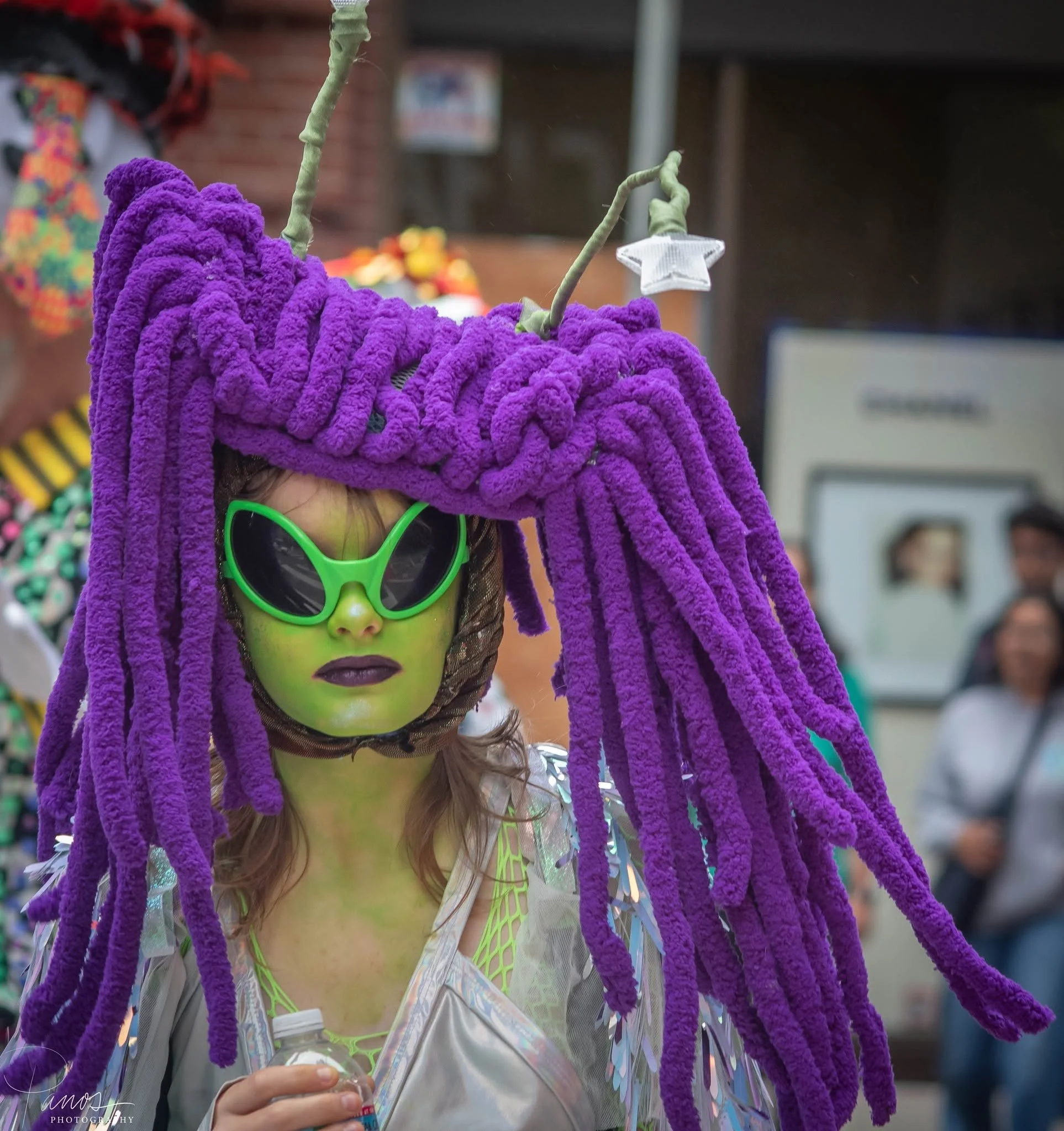 Festival participant wearing green sunglasses and an elaborate purple costume at the How Weird Street Faire in San Francisco.