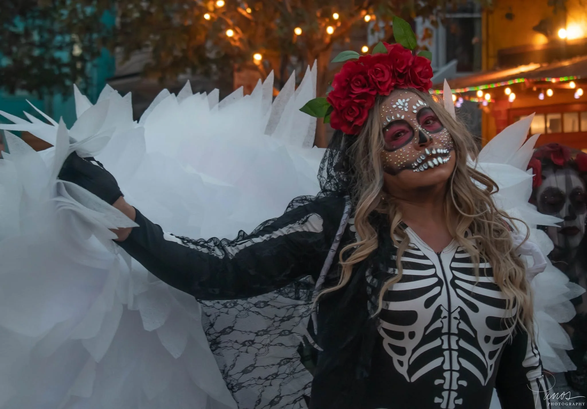 Participant wearing a skeleton costume, red flowers and Día de los Muertos face paint in San Francisco.