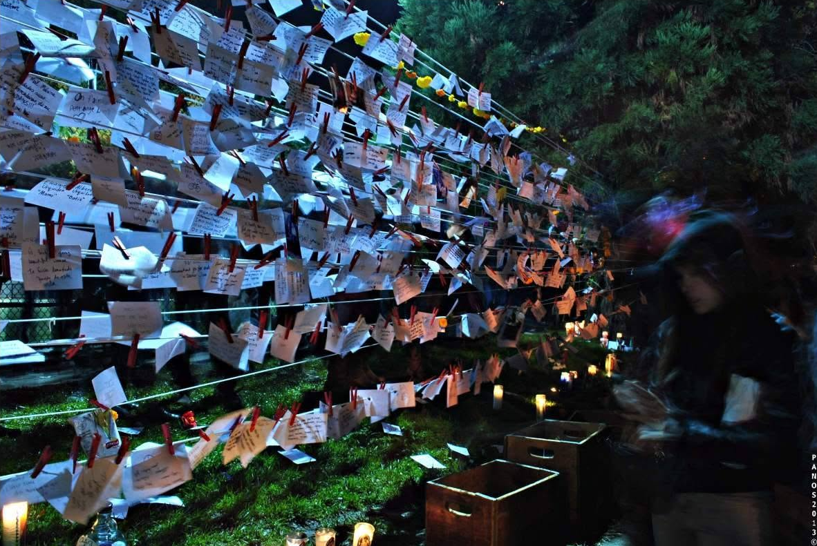 Handwritten remembrance messages displayed with candles at a Día de los Muertos observance in San Francisco.
