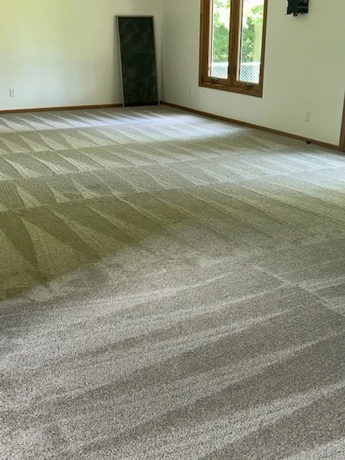 Empty room with a window, a blackboard leaning against the wall, and freshly vacuumed beige carpet with visible vacuum lines.