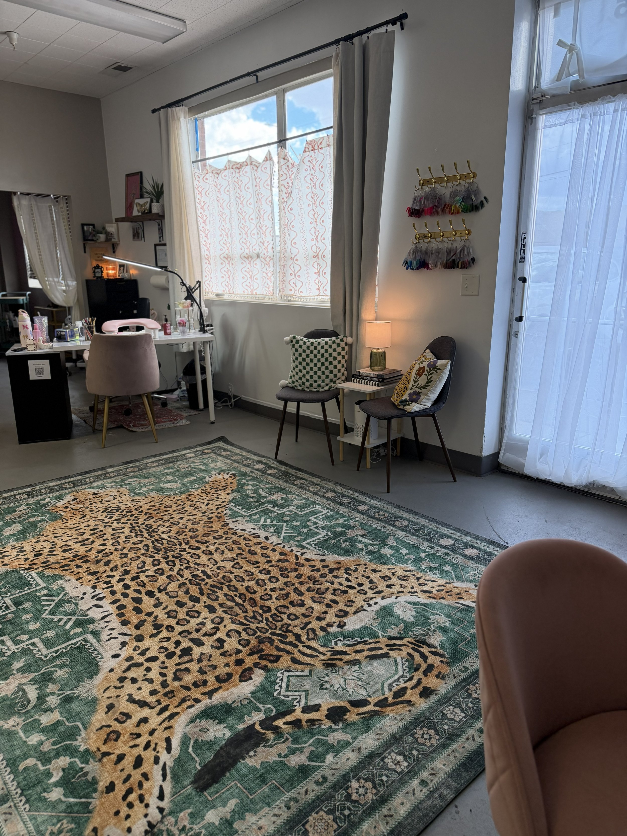 Eclectic nail salon interior with colorful rugs, pink seating, and independent artist workstations at Pinché Collective.