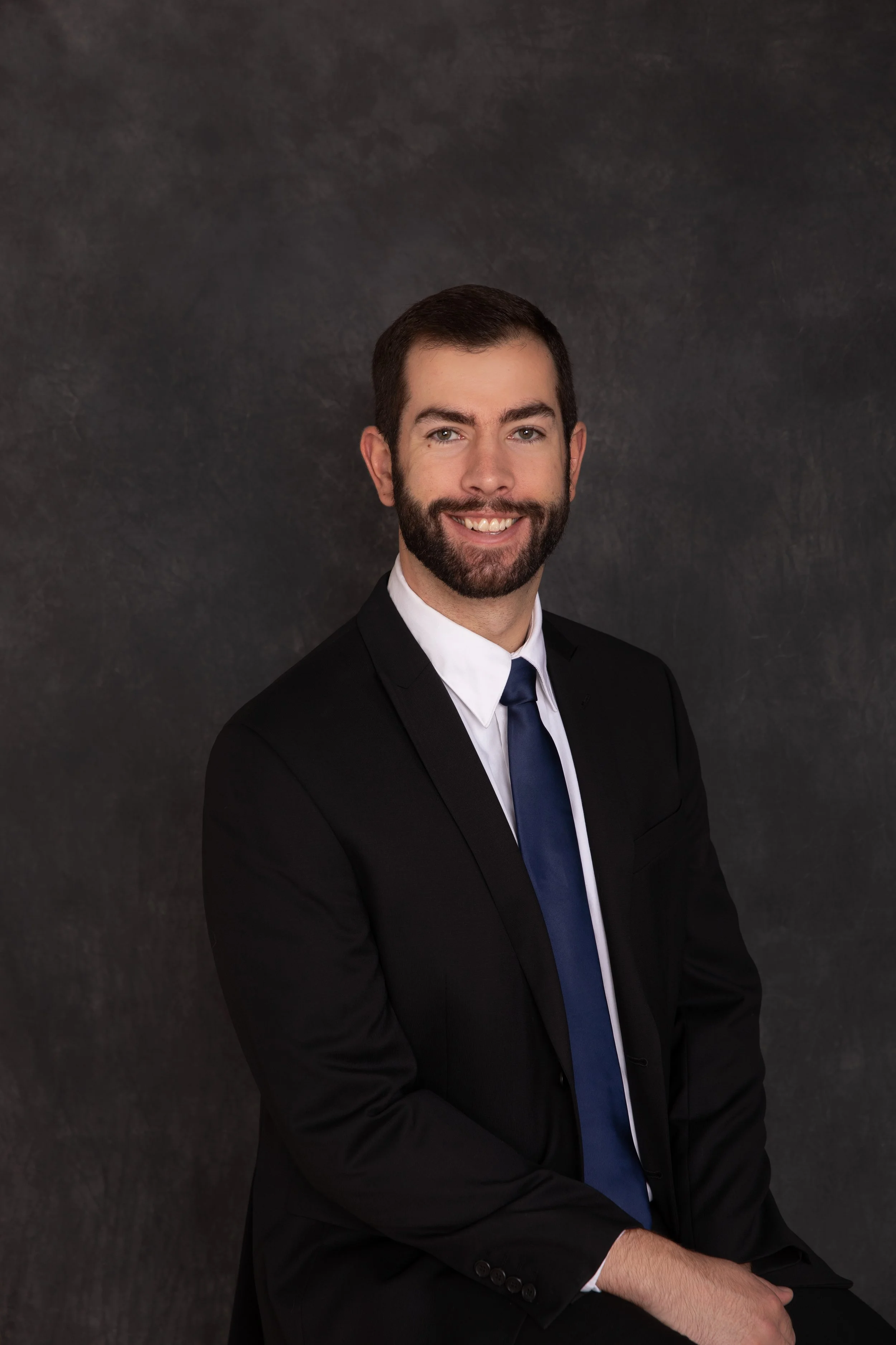 Professional headshot of Blake Williams in a black jacket and blue tie