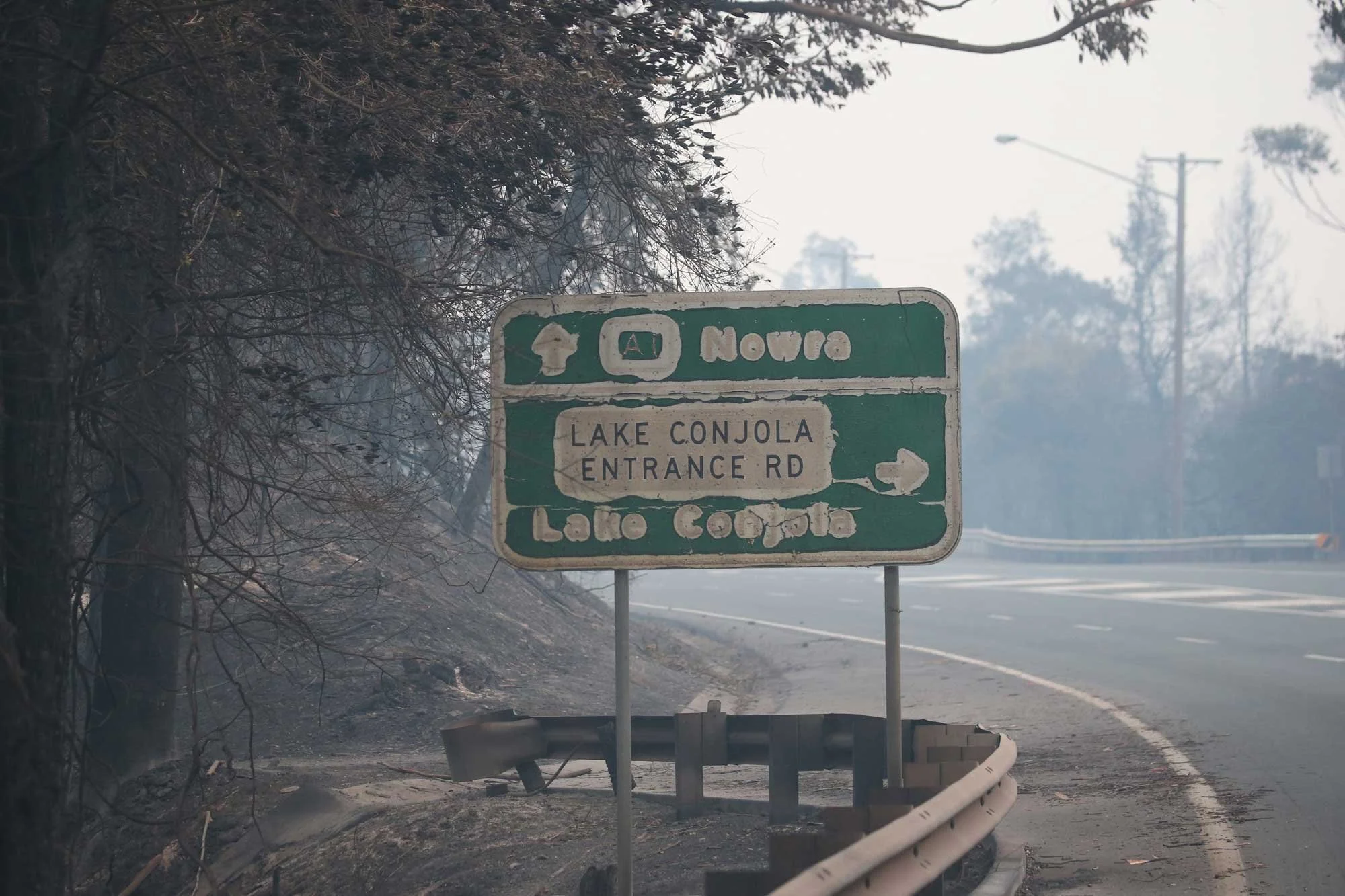  Burnt road sign at the Lake Conjola intersection on a closed Princes Highway with no traffic south of Nowra this morning.   Wednesday 1st January 2020. Guardian Australia. 