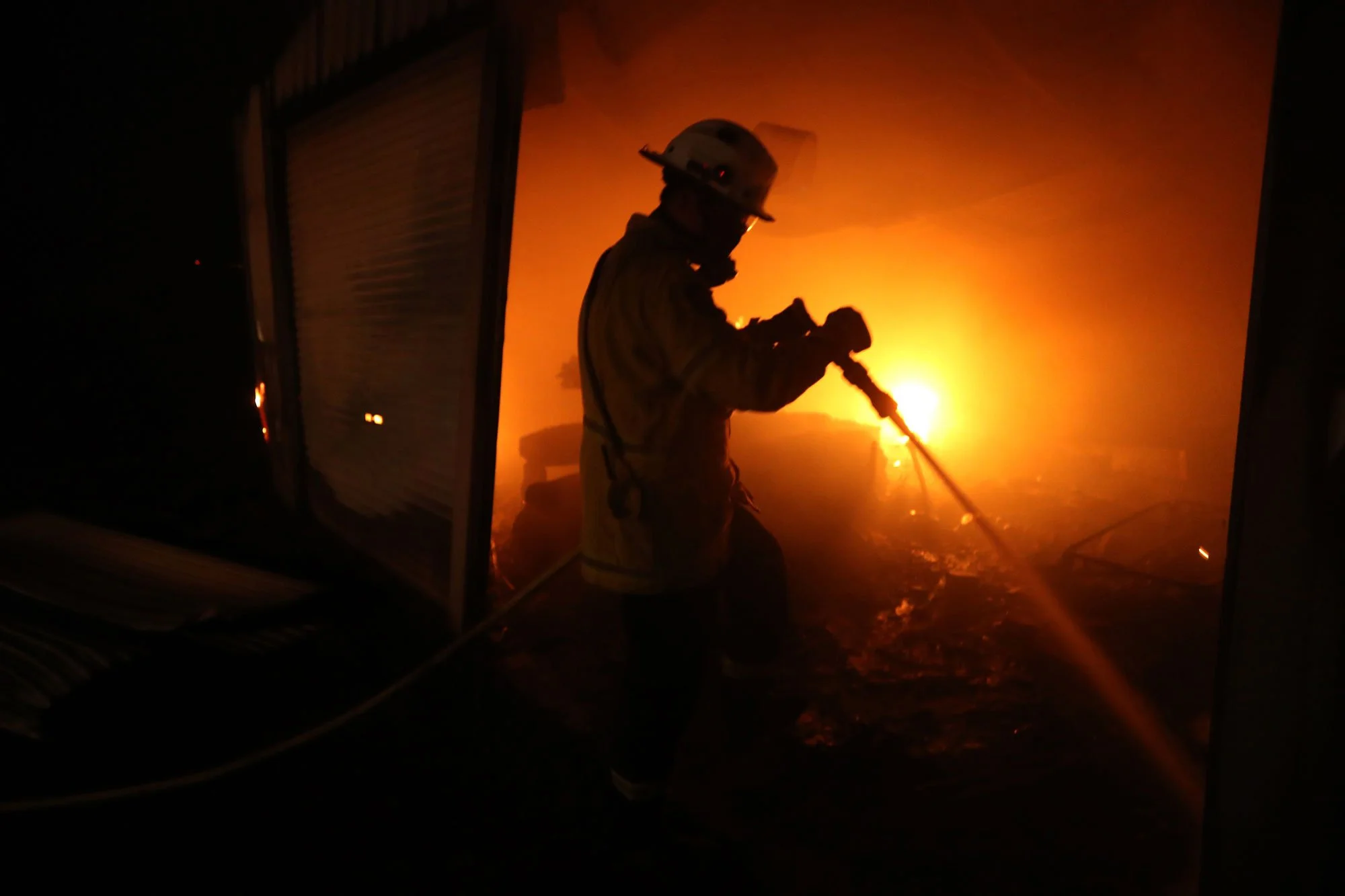  Horsley Park RFS Fire fighter Daniel Knox extinguishes a fire in a garage which was well alight when they arrived on a property near Potato Point on NSW South Coast.   Thursday 23rd January 2020. Guardian Australia 