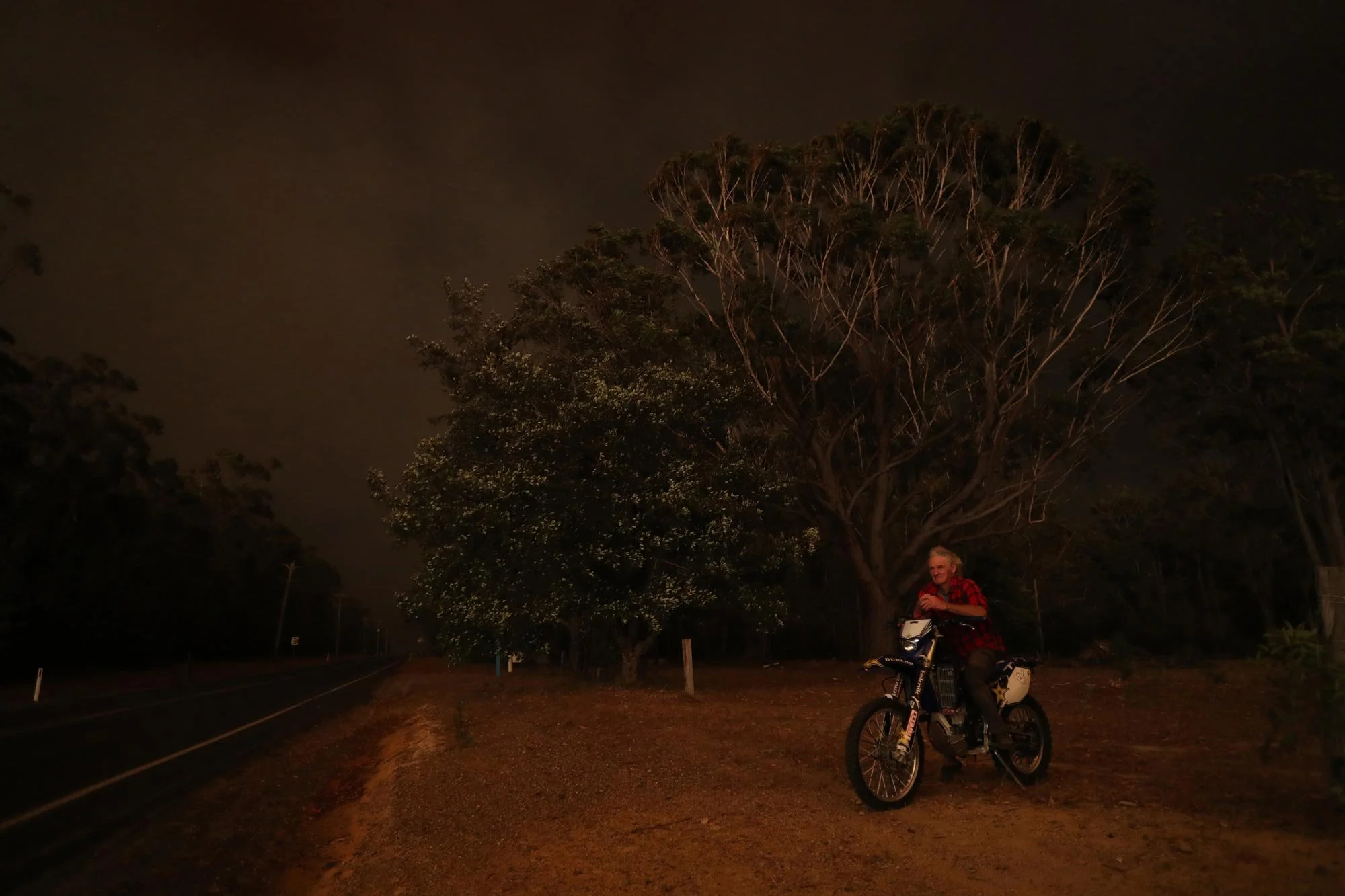  Night from Day-Peter Nicol watches the approaching fire from the front of his property along the Sussex inlet road south of Nowra this afternoon.   Tuesday 31st December 2019. Guardian Australia. 