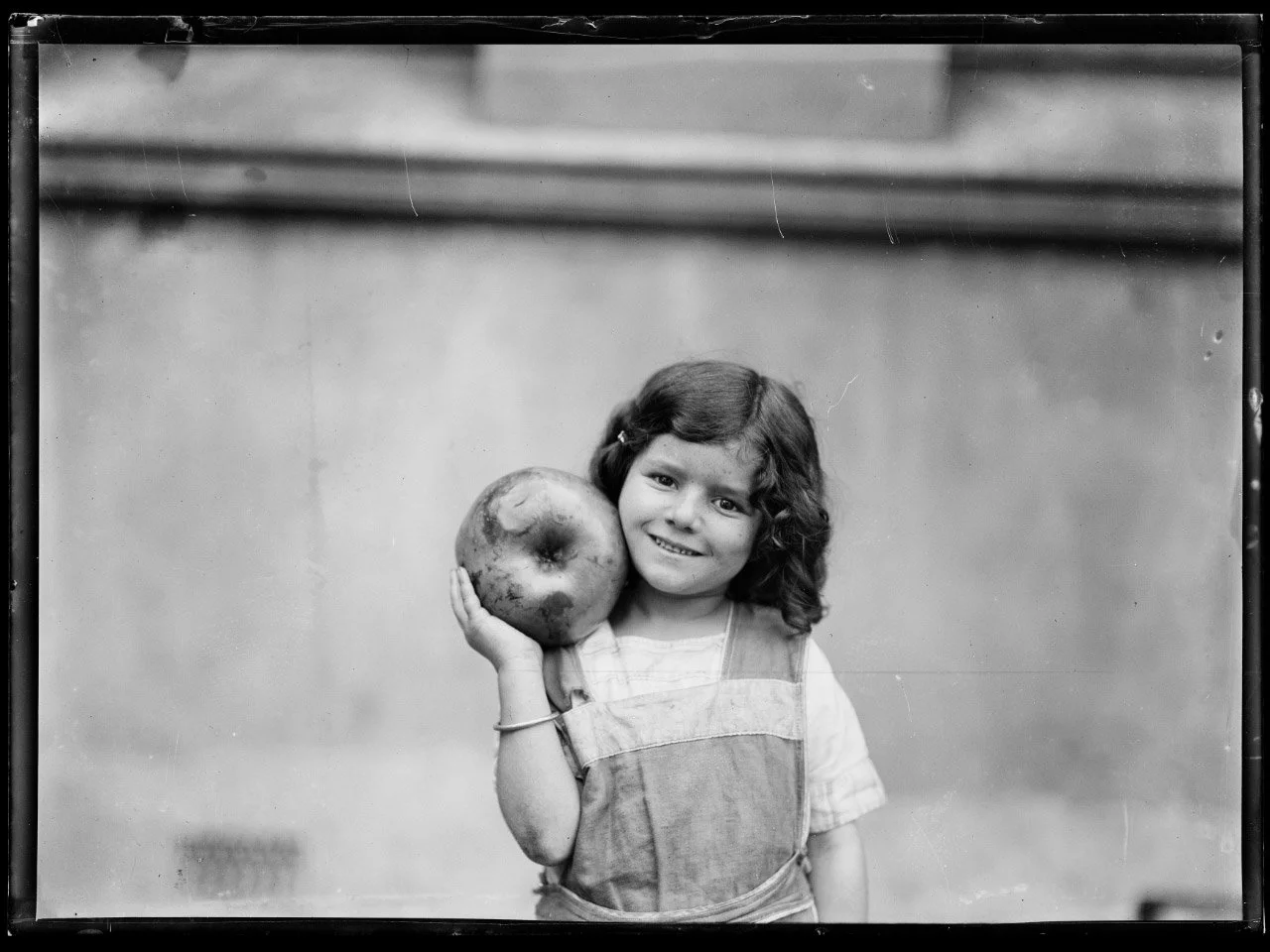 Fairfax Corporation, Young girl holding a large apple beside her head, New South Wales, ca. 1930s, nla.gov.au/nla.obj-163350126