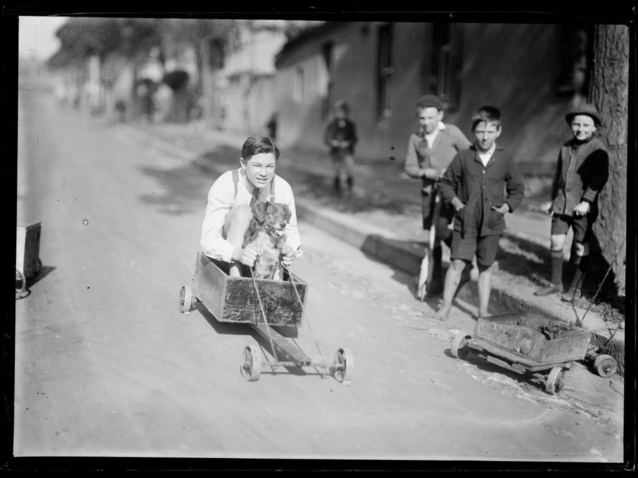 Fairfax Corporation, Boy and dog in a billycart race past other children on a suburban street, Sydney, ca. 1920s, nla.gov.au/nla.obj-162855139