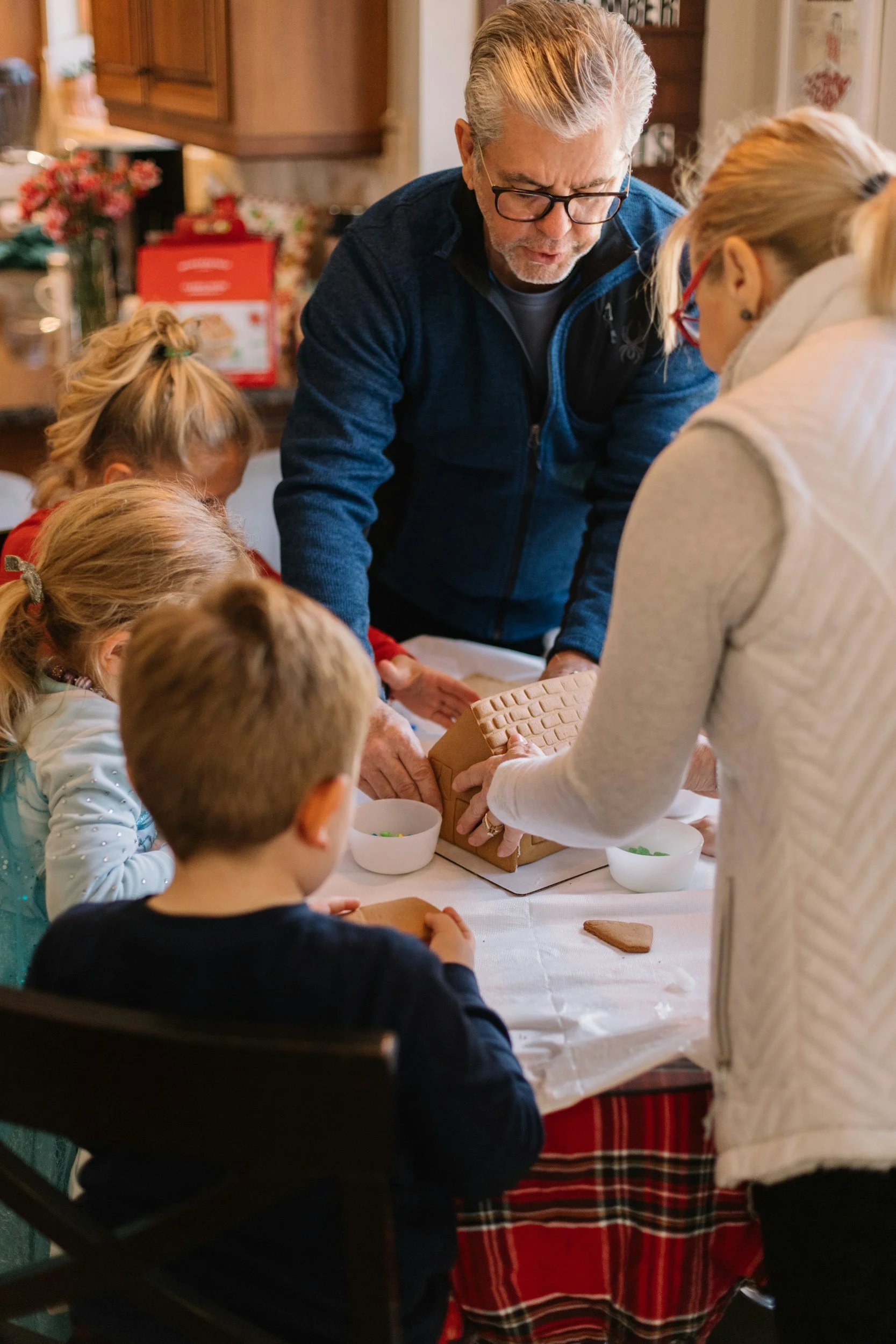 A group of children and two adults decorating gingerbread cookies at a table during Christmas.