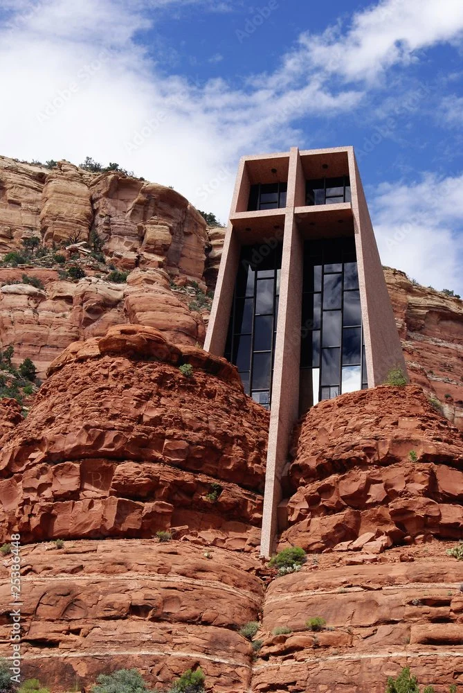 Modern FLW building with large glass windows built into a red rock mountain landscape.