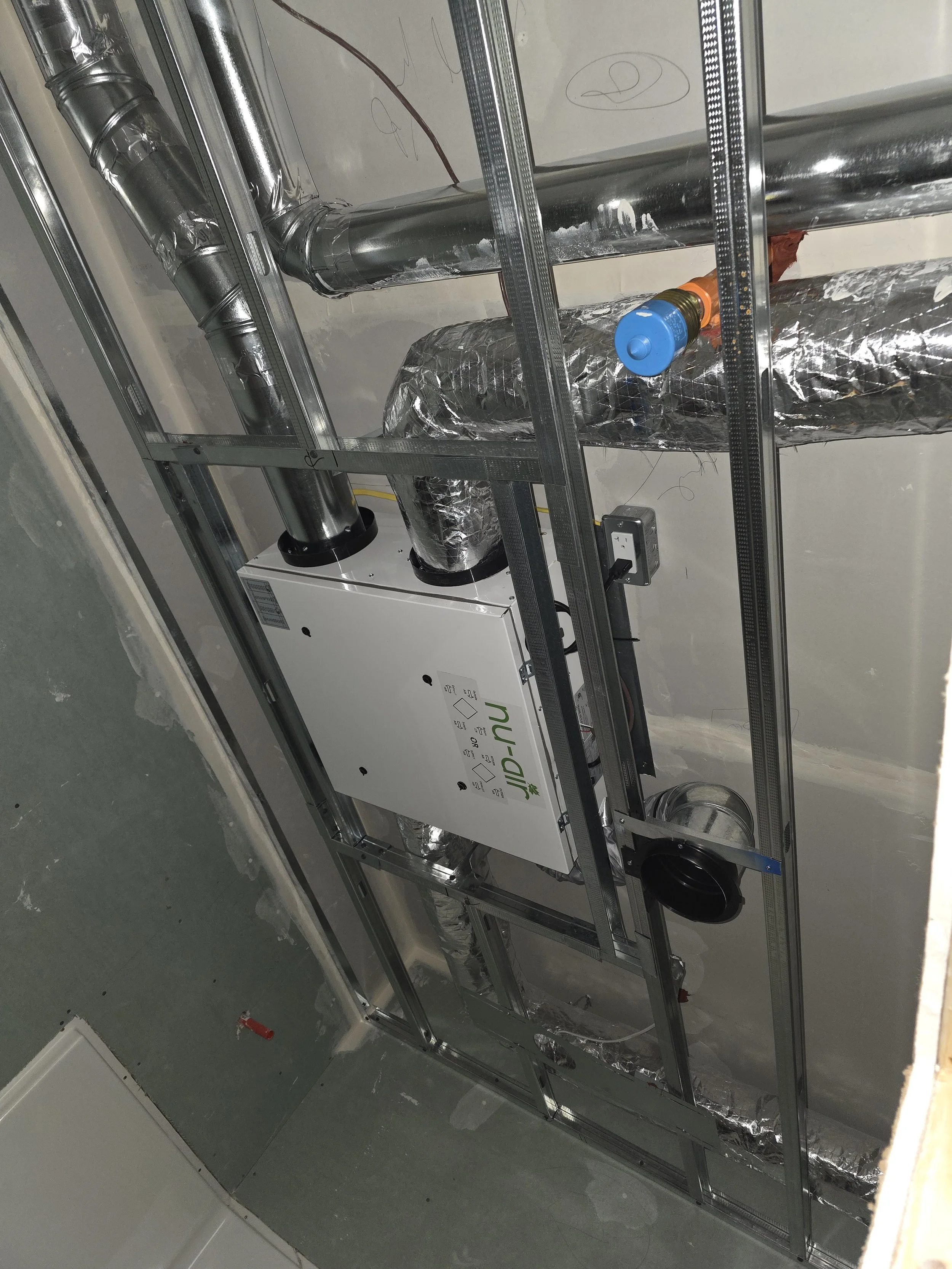 Construction ceiling with metal framing, insulated ducts, and a Nu-Cal heater mounted on the wall.