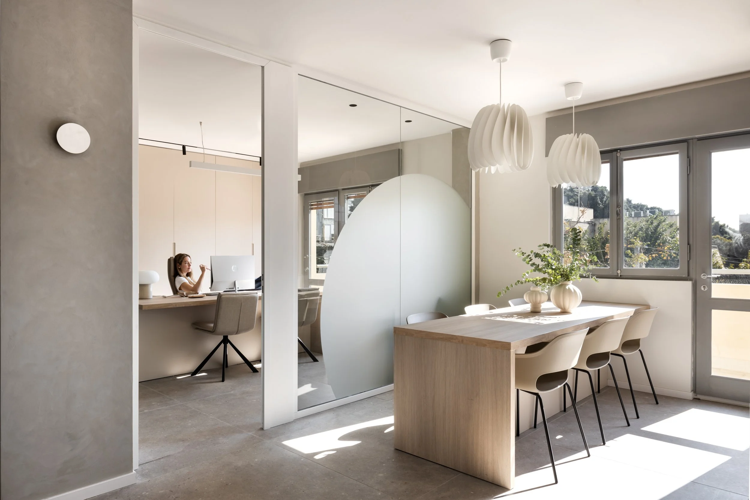 Modern boutique office interior with wood desk, sculptural lighting, and glass-partition workspace design